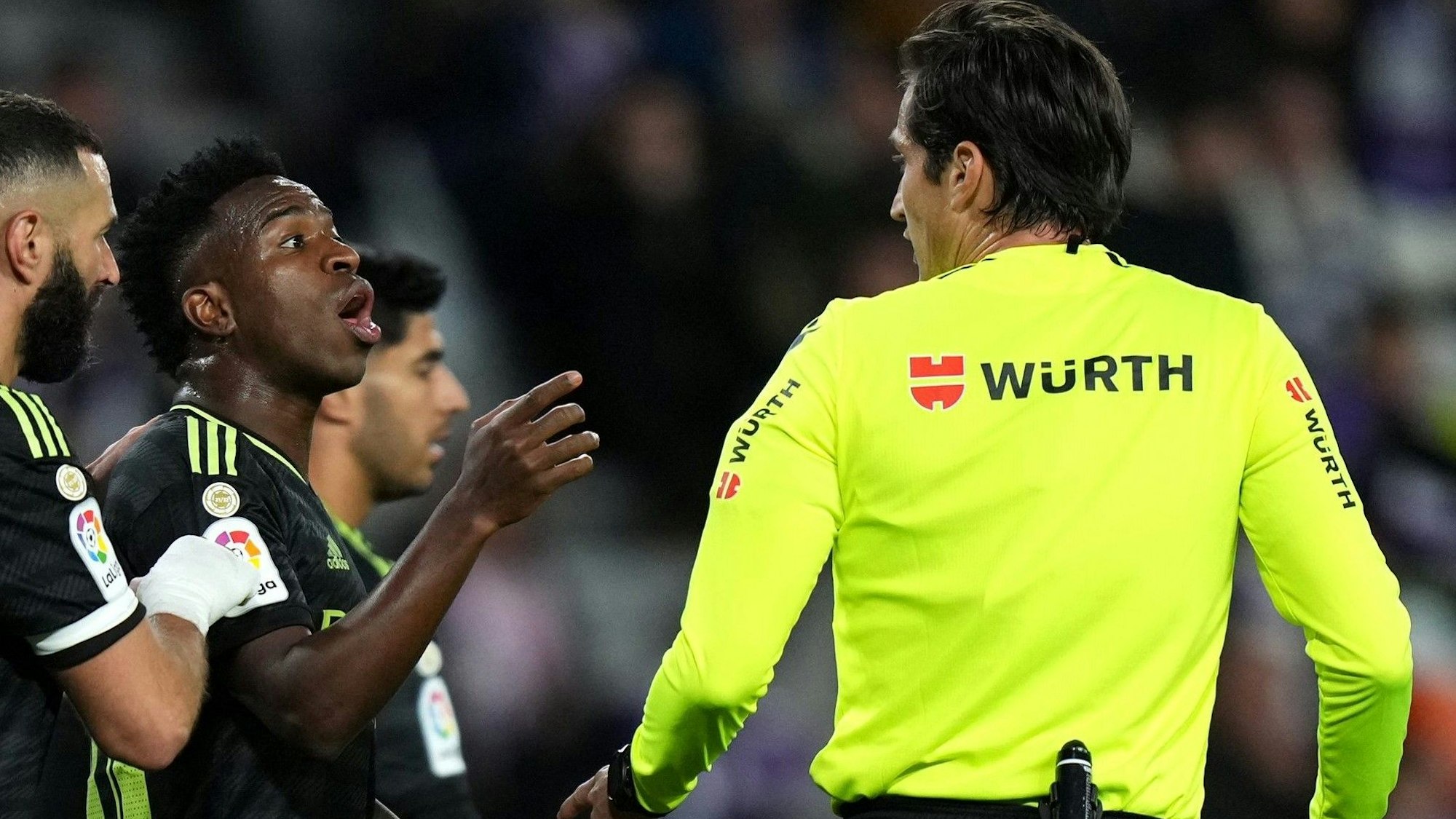 Vinícius Júnior (M.) im Spiel bei Real Valladolid mit Madrid-Kollege Karim Benzema bei einer Diskussion mit Schiedsrichter José Luis Munuera Montero.
