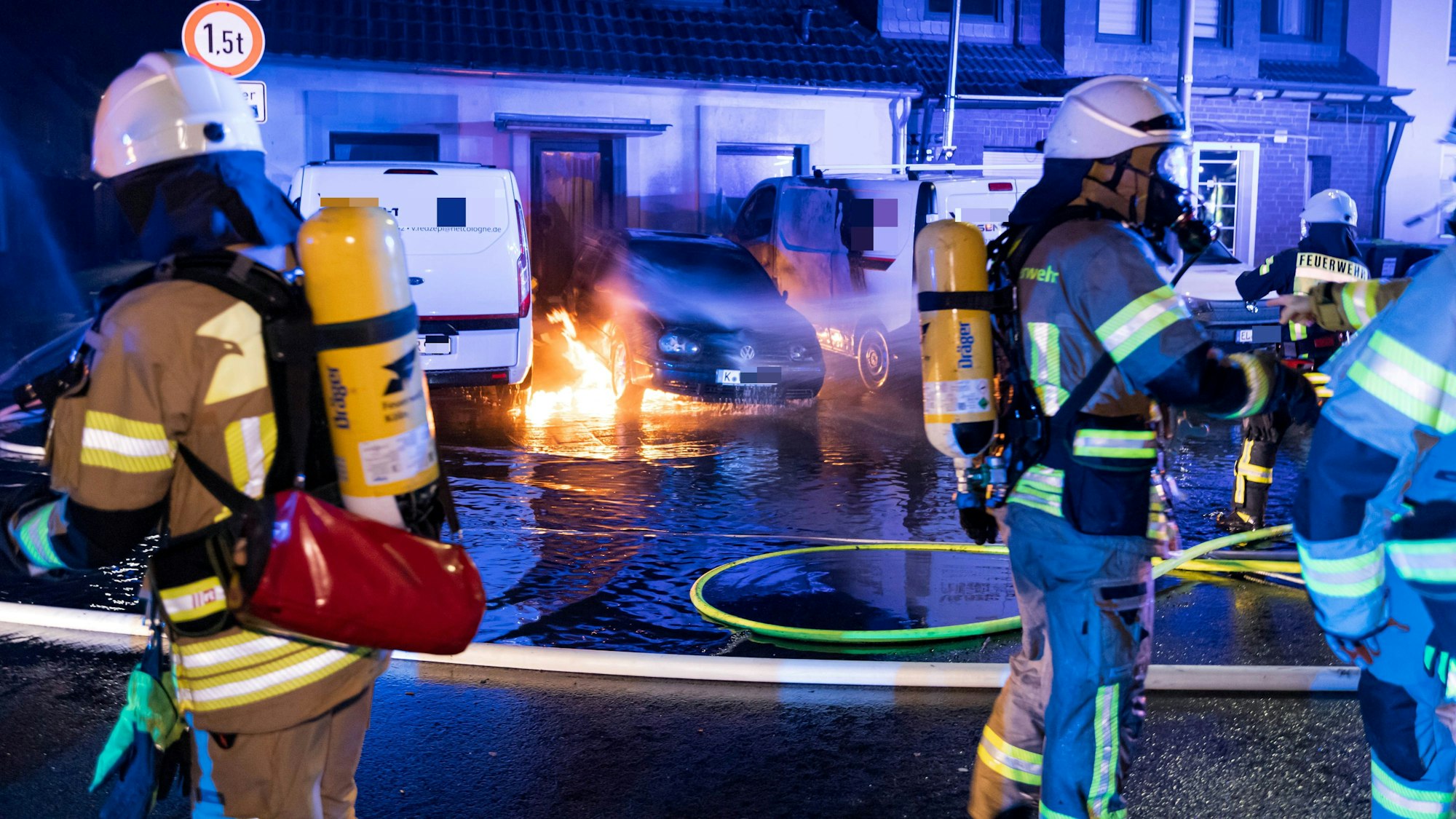 Einsatzkräfte der Feuerwehr löschen ein brennendes Auto.