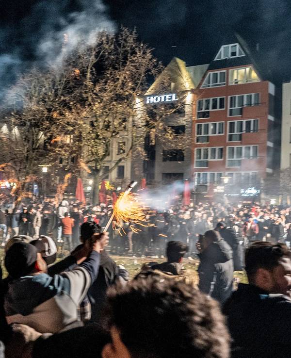 Hunderte Menschen stehen in Köln auf einer großen Platzfläche und zünden Feuerwerk.