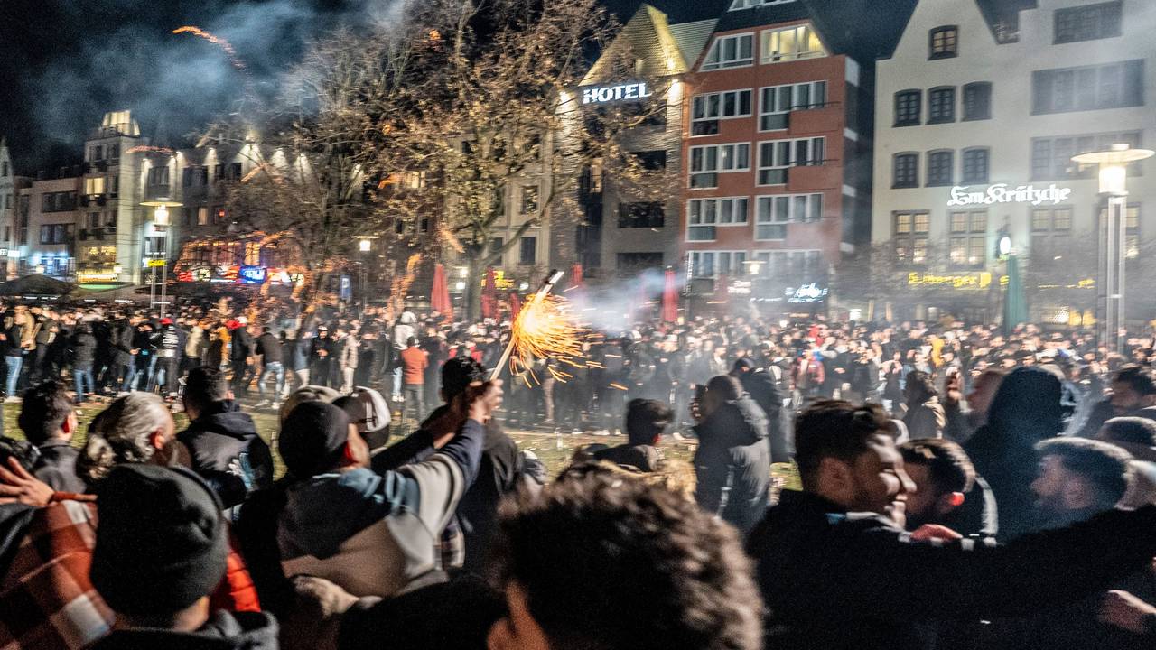 Hunderte Menschen stehen in Köln auf einer großen Platzfläche und zünden Feuerwerk.