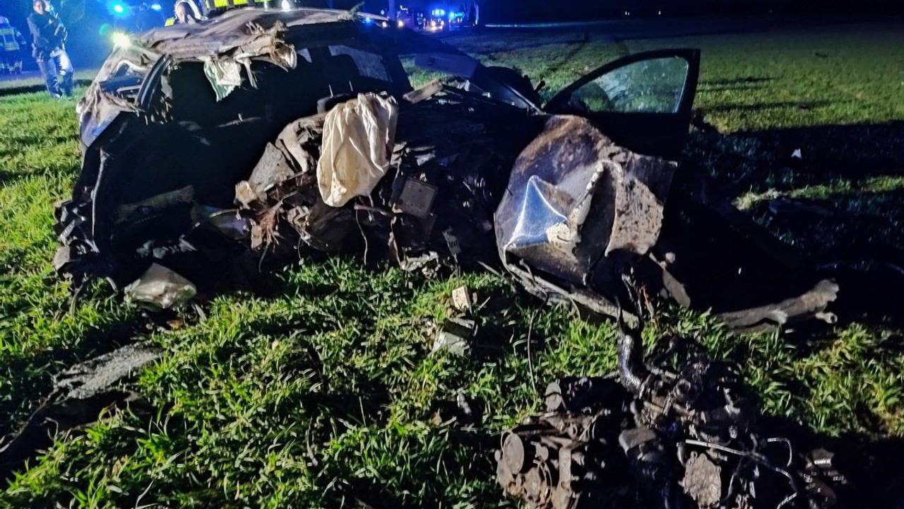 Trümmerteile eines Autos liegen auf einer Wiese.