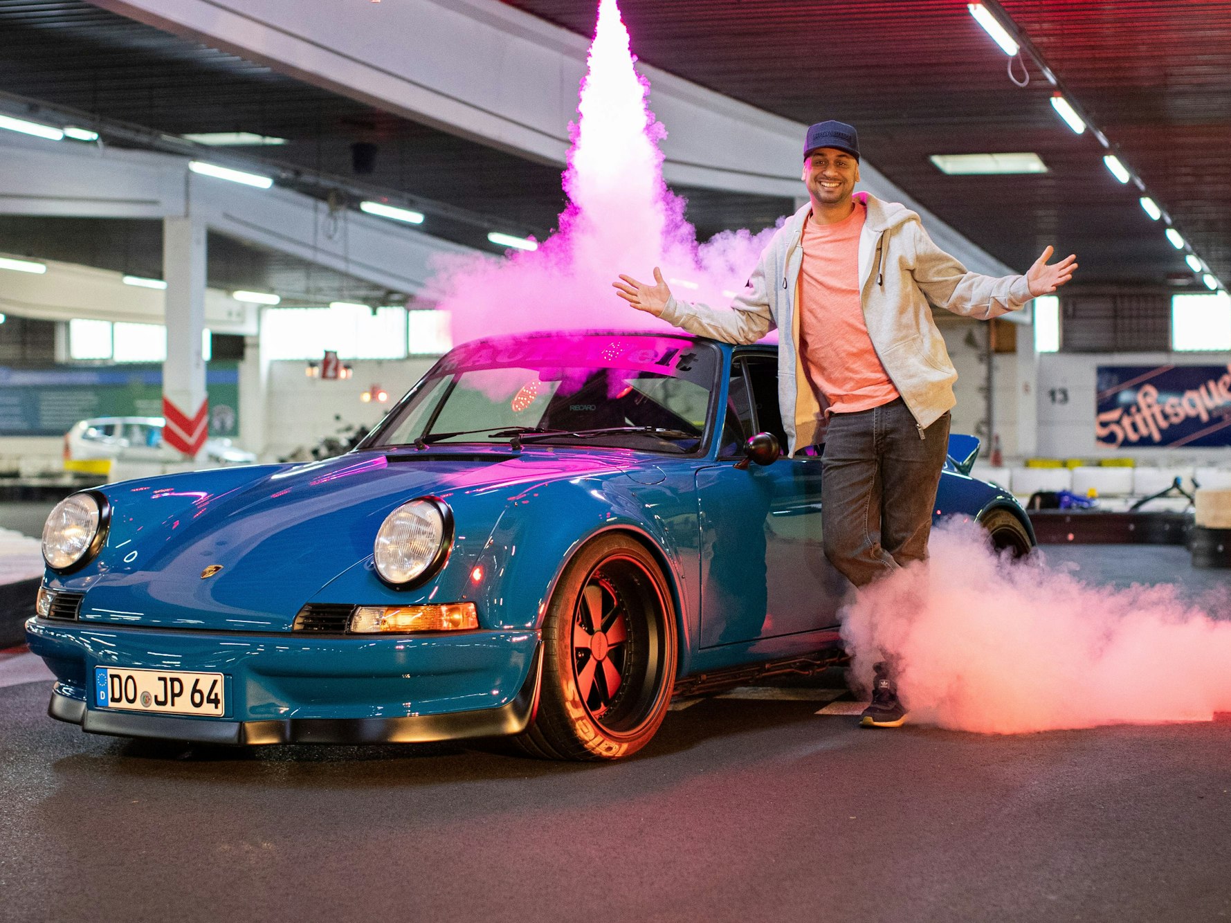 Tuningprofi Jean Pierre „JP“ Kraemer posiert im Daytona Kart-Center vor einem Porsche RWB Backdate.
