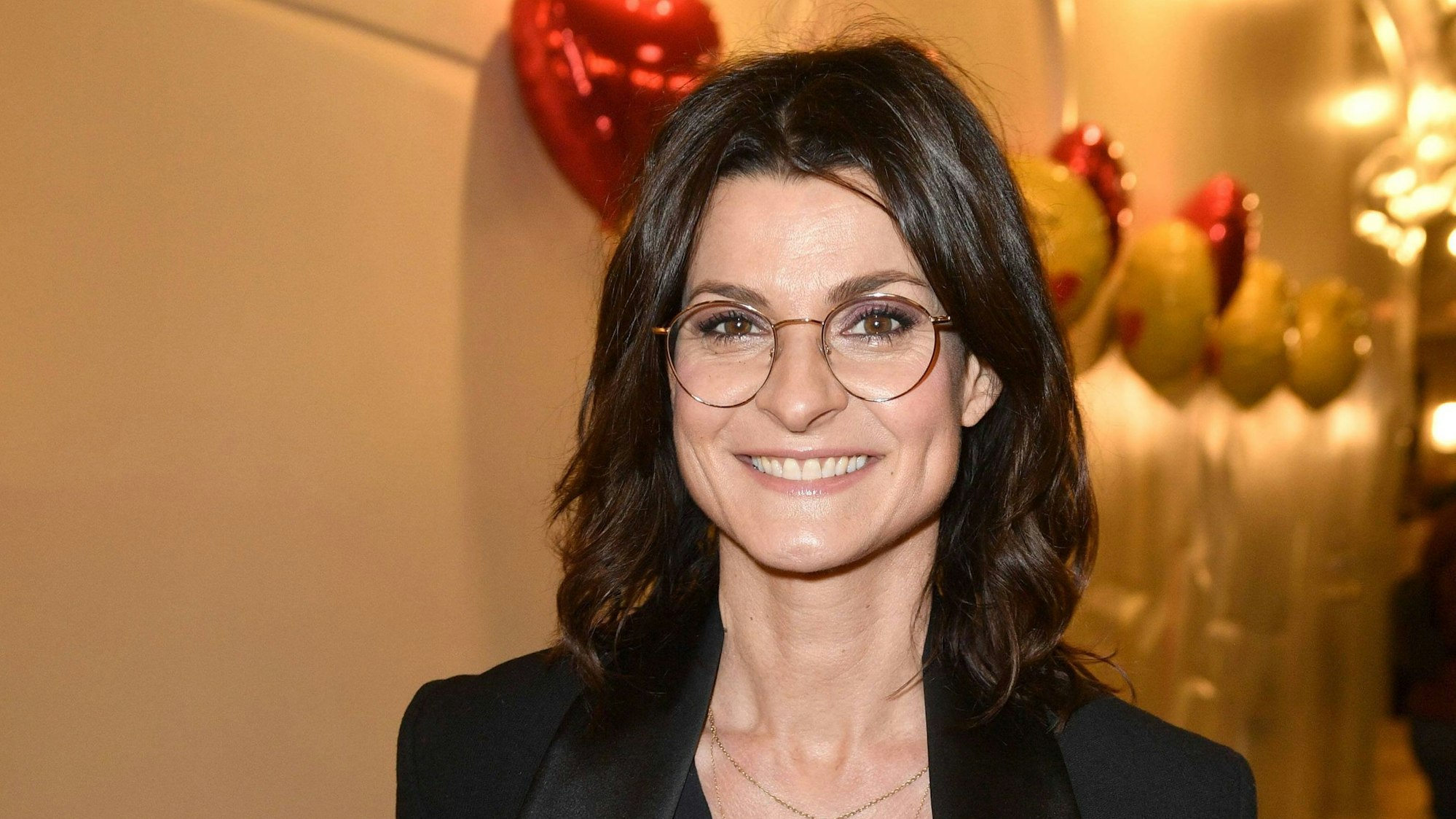 Marlene Lufen lächelt in einem schwarzen Einteiler in die Kamera.