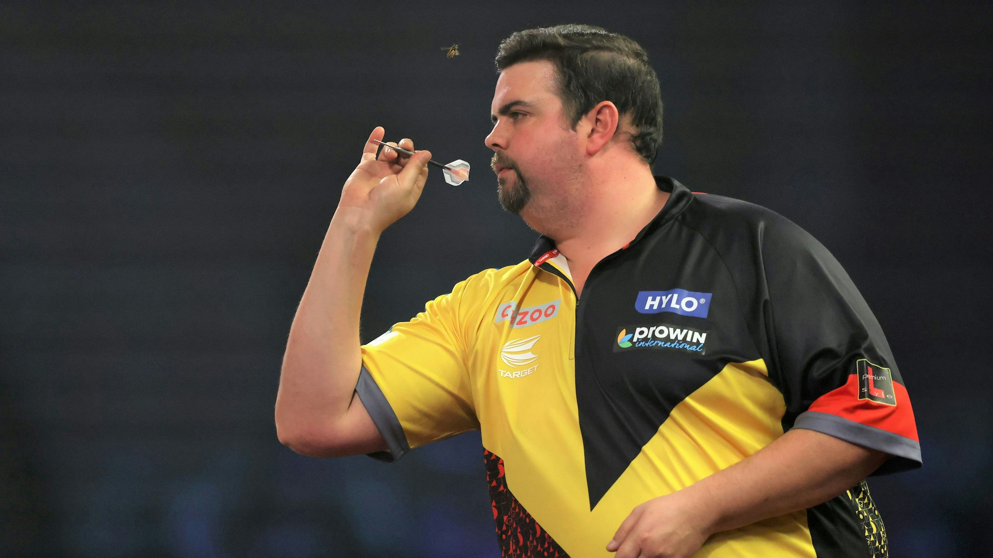 Gabriel Clemens beim Wurf im Viertelfinale der Darts-WM. Ganz ungestört ist er dabei nicht, wie der Blick in Richtung Stirn zeigt.