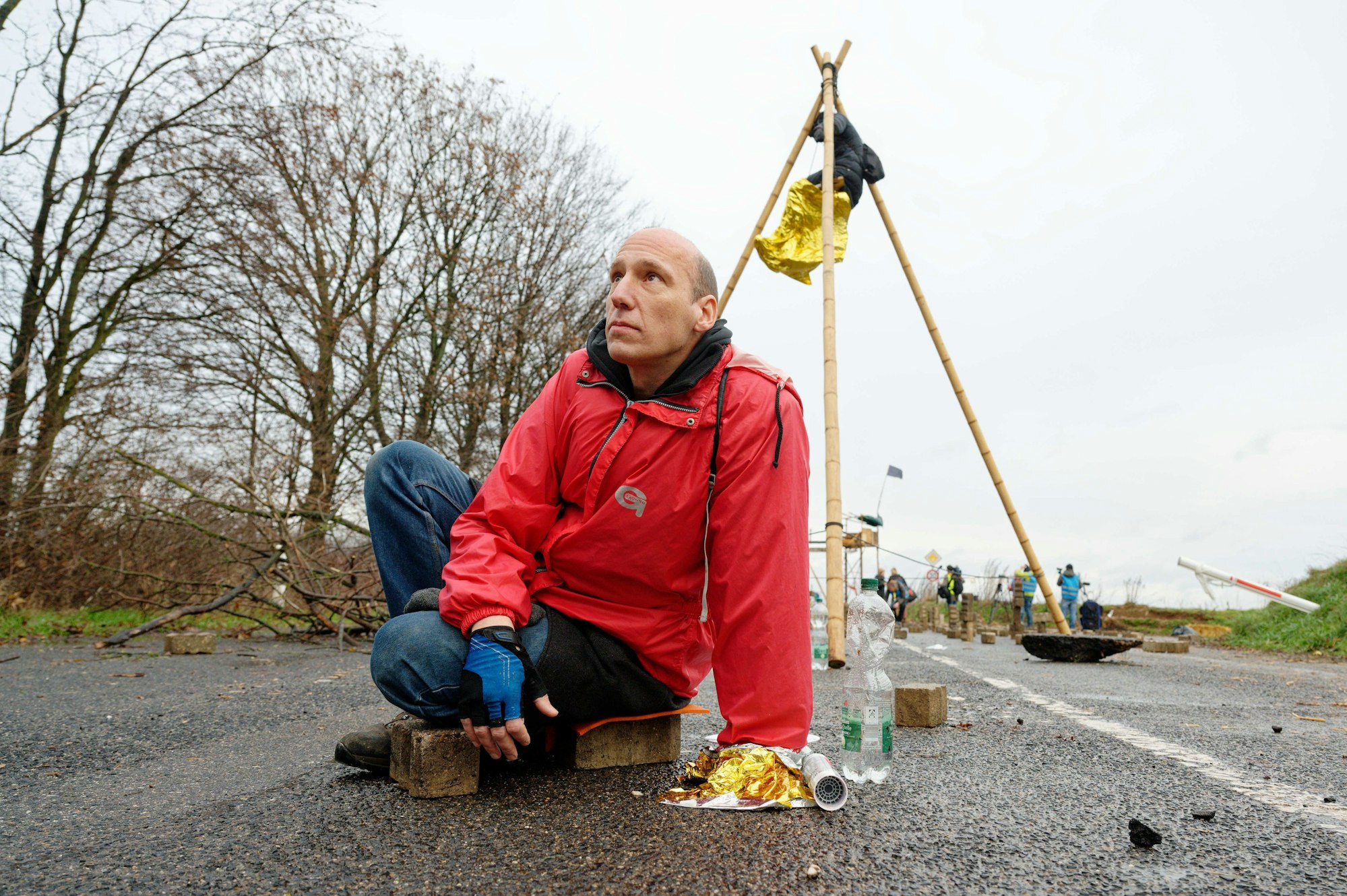 Ein Aktivist der Letzten Generation hat sich auf einer der Zufahrten in Richtung Lützerath mit einer Hand an der Straße festgeklebt.