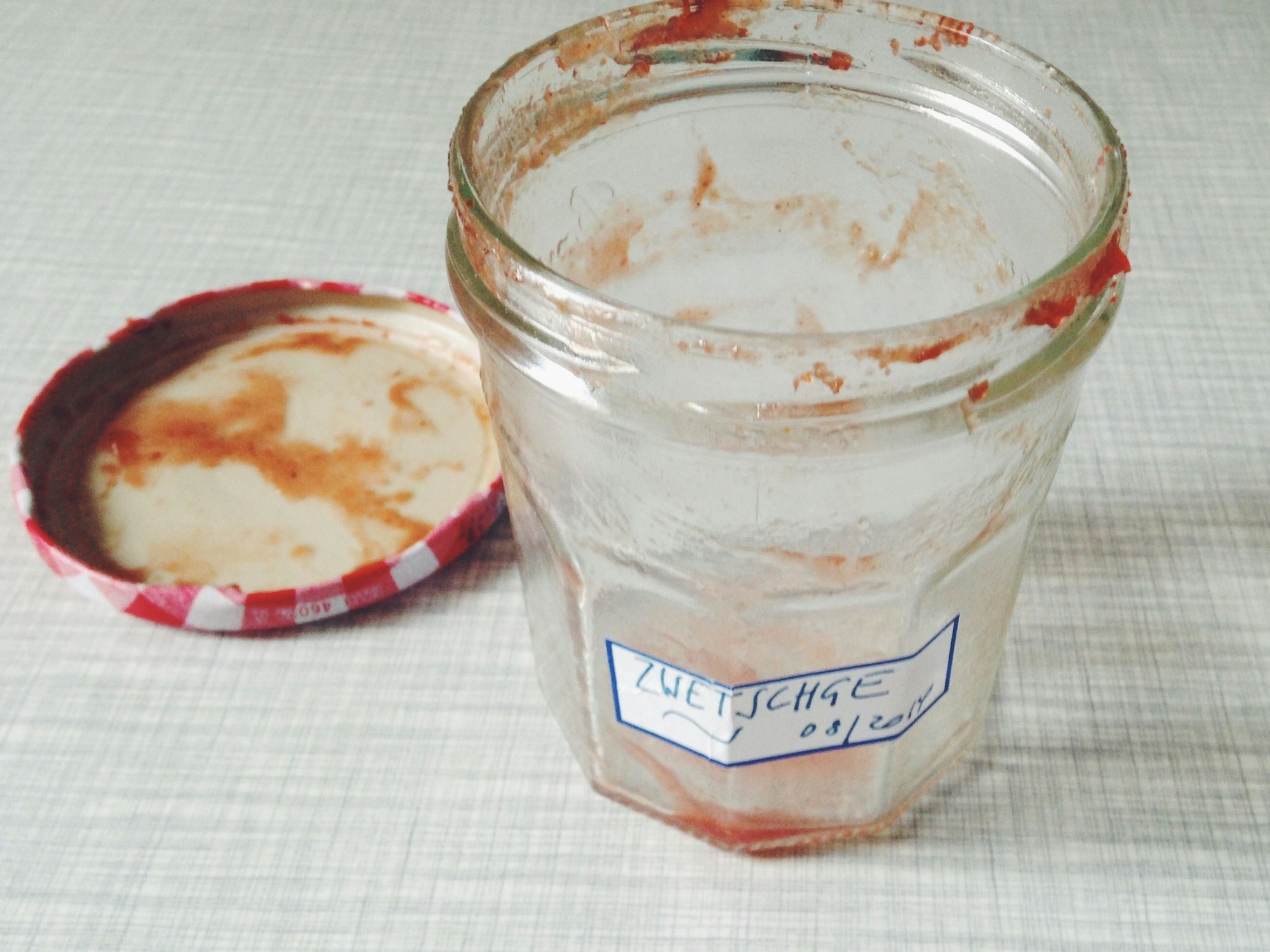 Ein leer gelöffeltes Marmeladenglas mit einem selbstgeschriebenen Etikett.