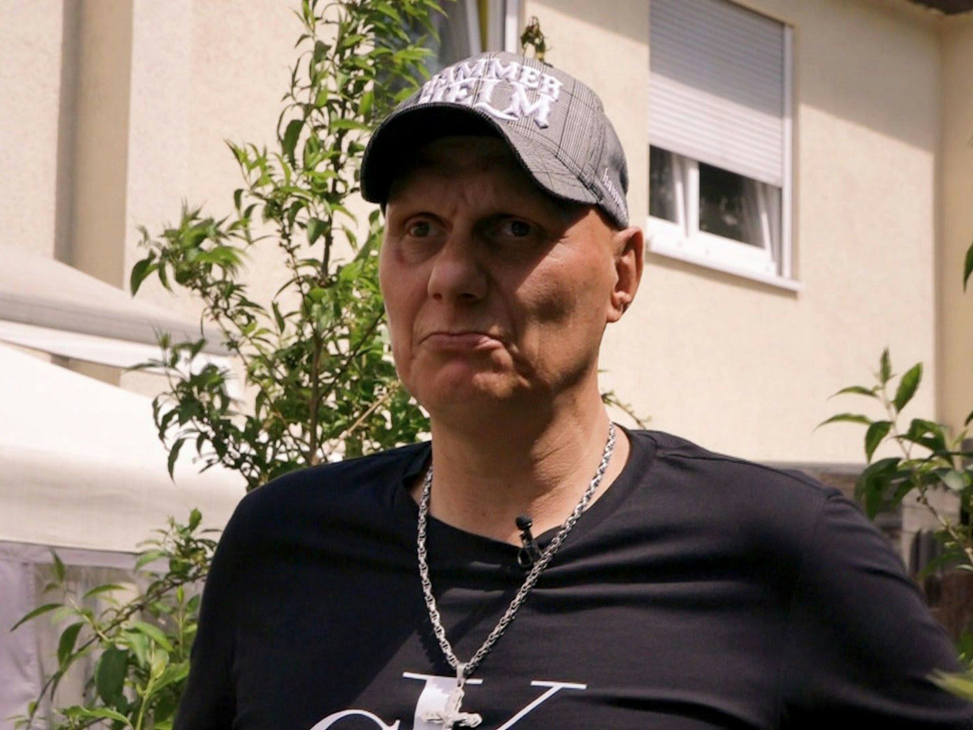 Elvis trägt eine Kappe und ein Kette um den Hals.