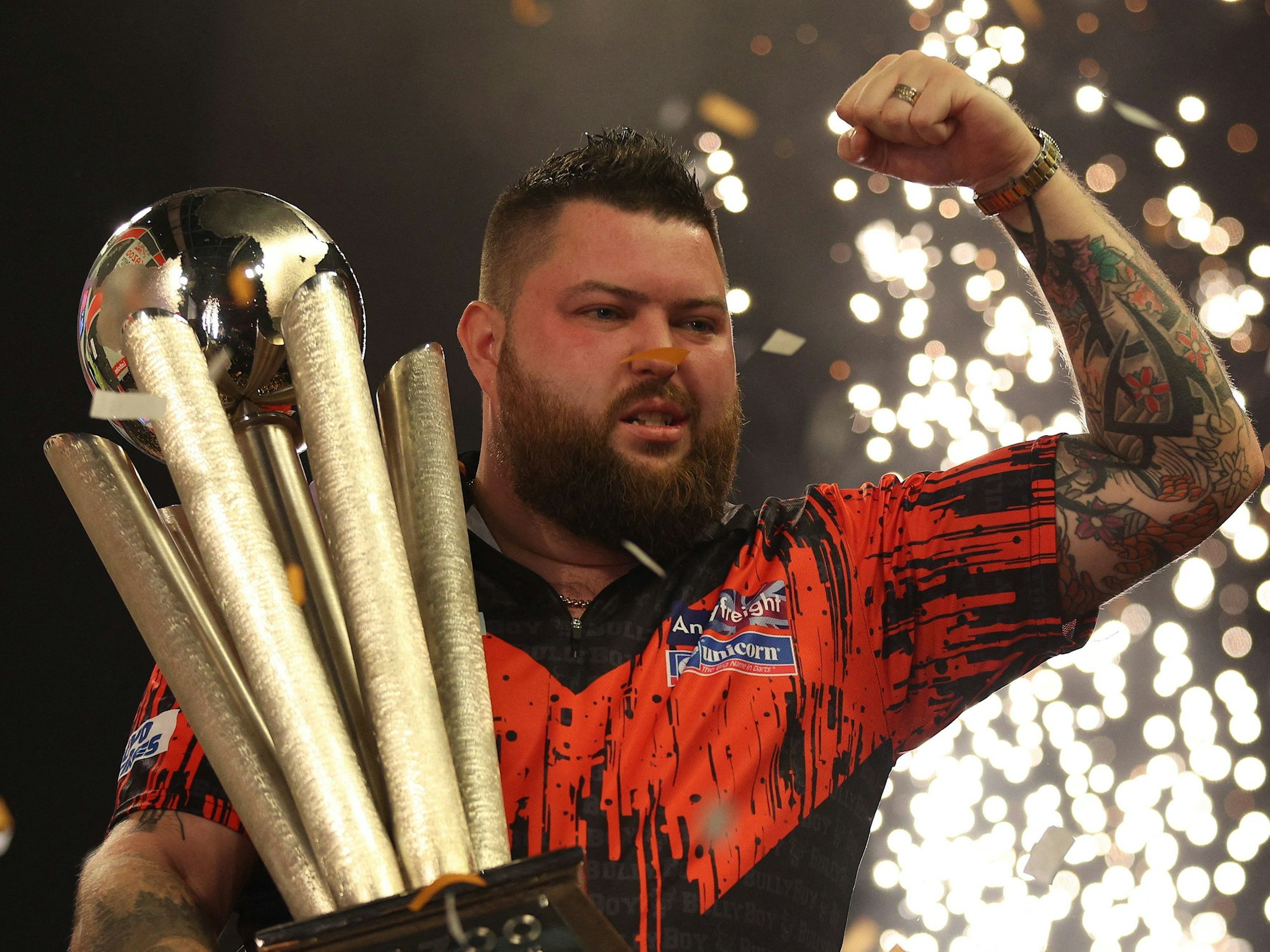 Michael Smith hält die Trophäe der Darts-WM im Arm.