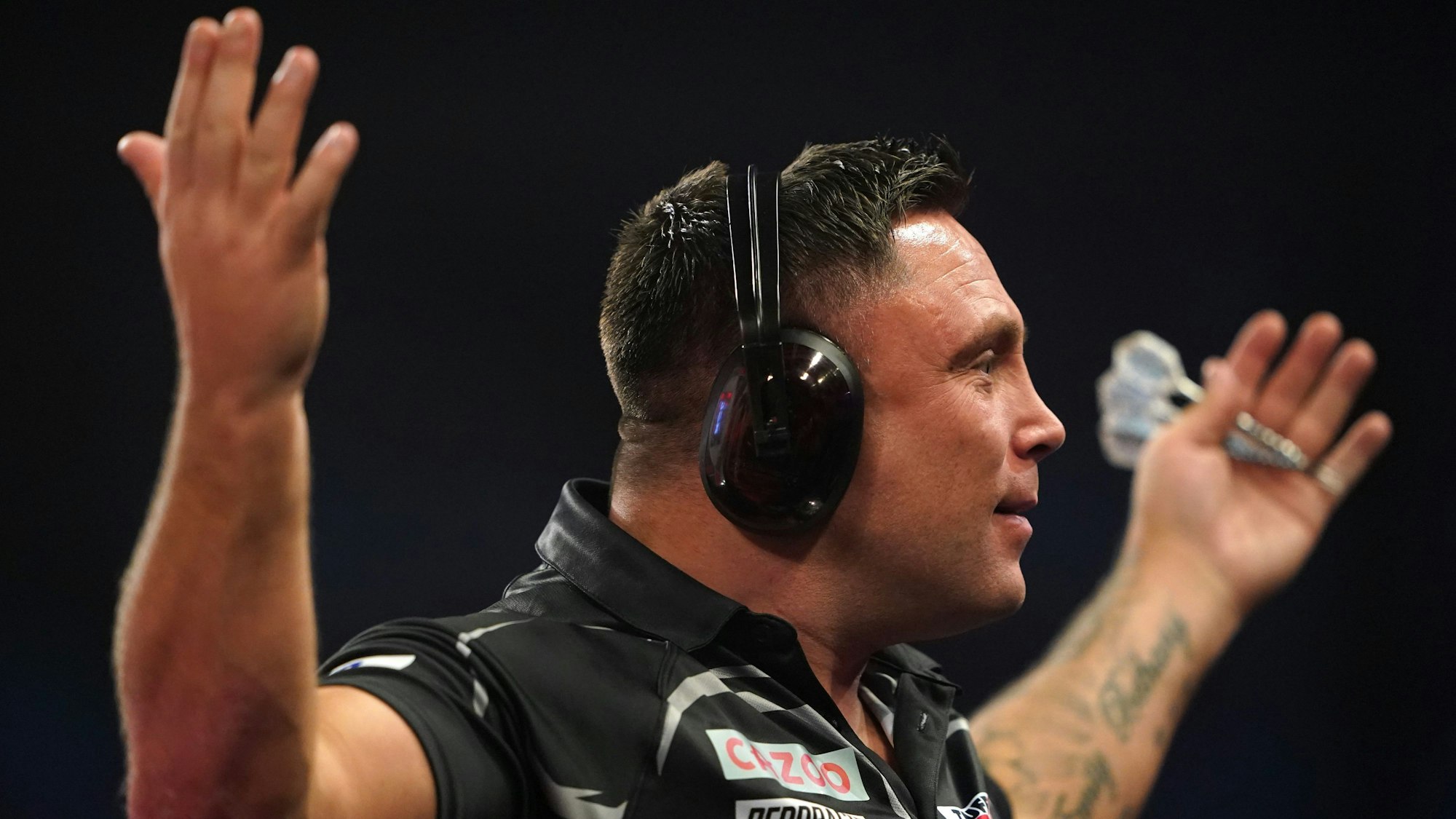 Gerwyn Price spielt das Viertelfinale der Darts-WM am Neujahrstag 2023 mit Gehörschutz und gestikuliert Richtung Publikum