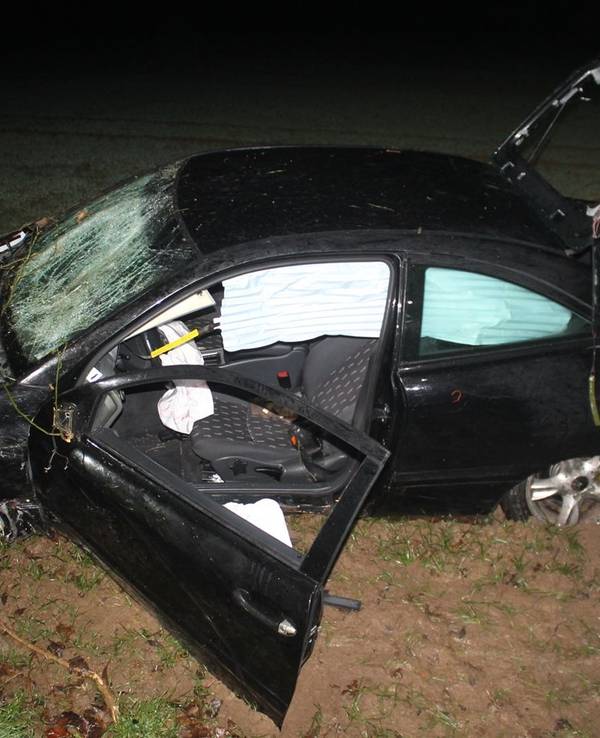 Schwer beschädigtes Auto liegt in einem Feld neben der Straße.