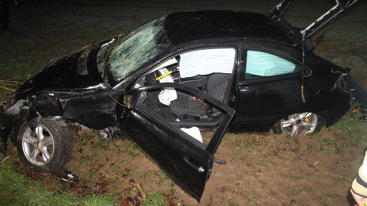 Schwer beschädigtes Auto liegt in einem Feld neben der Straße.