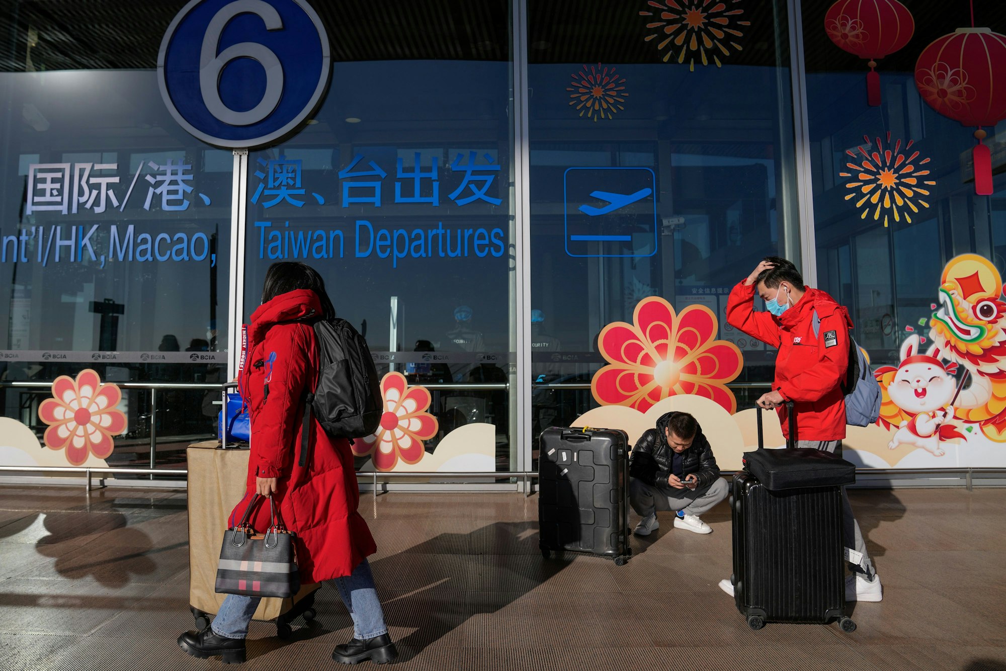 Reisende mit Mund-Nasen-Schutz rollen Gepäck am internationalen Abflugterminal am Hauptstadtflughafen.