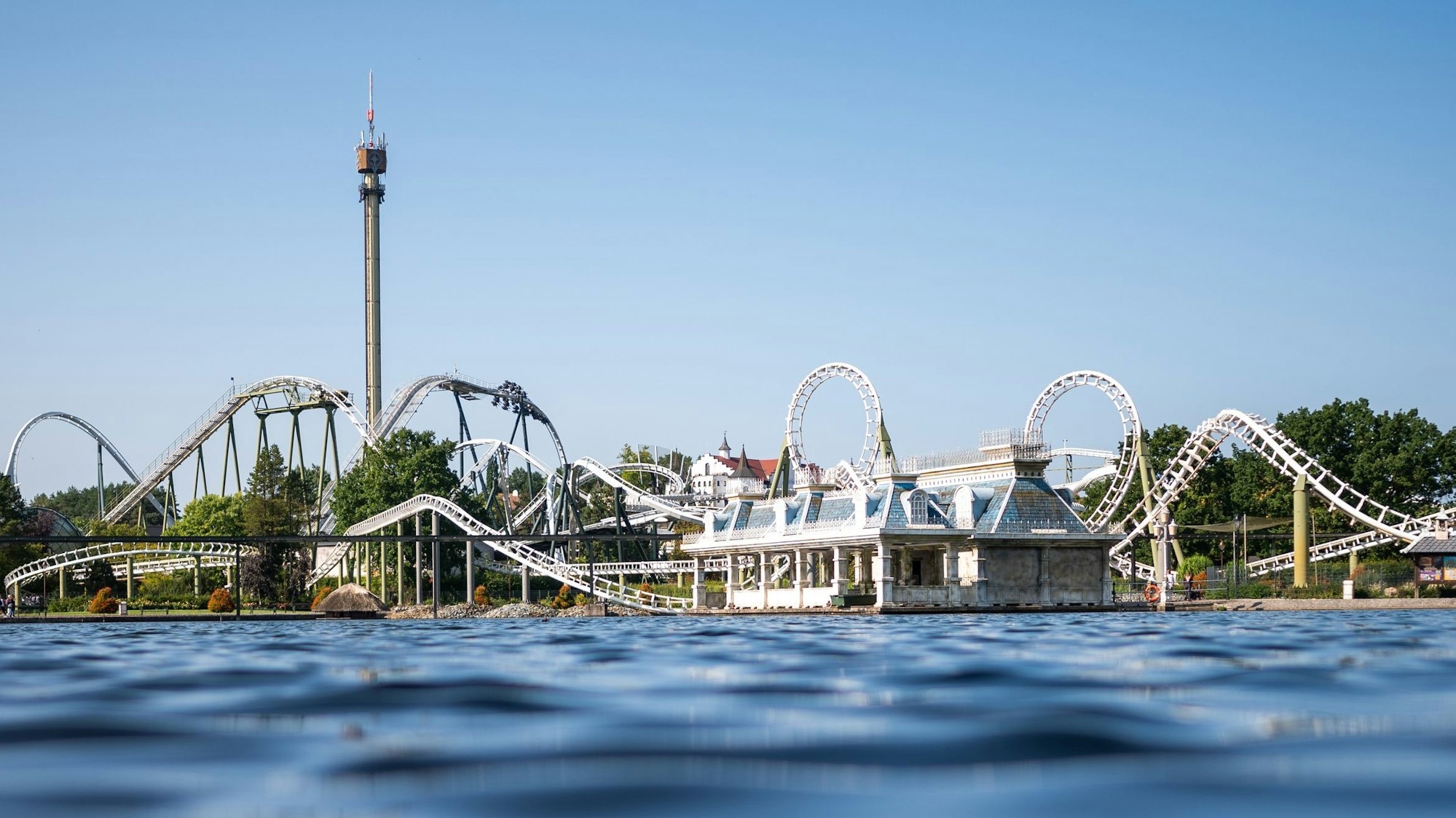 Eine Achterbahn im Heide Park Soltau ist zu sehen. Das Foto ist von einem Gewässer aus aufgenommen worden.