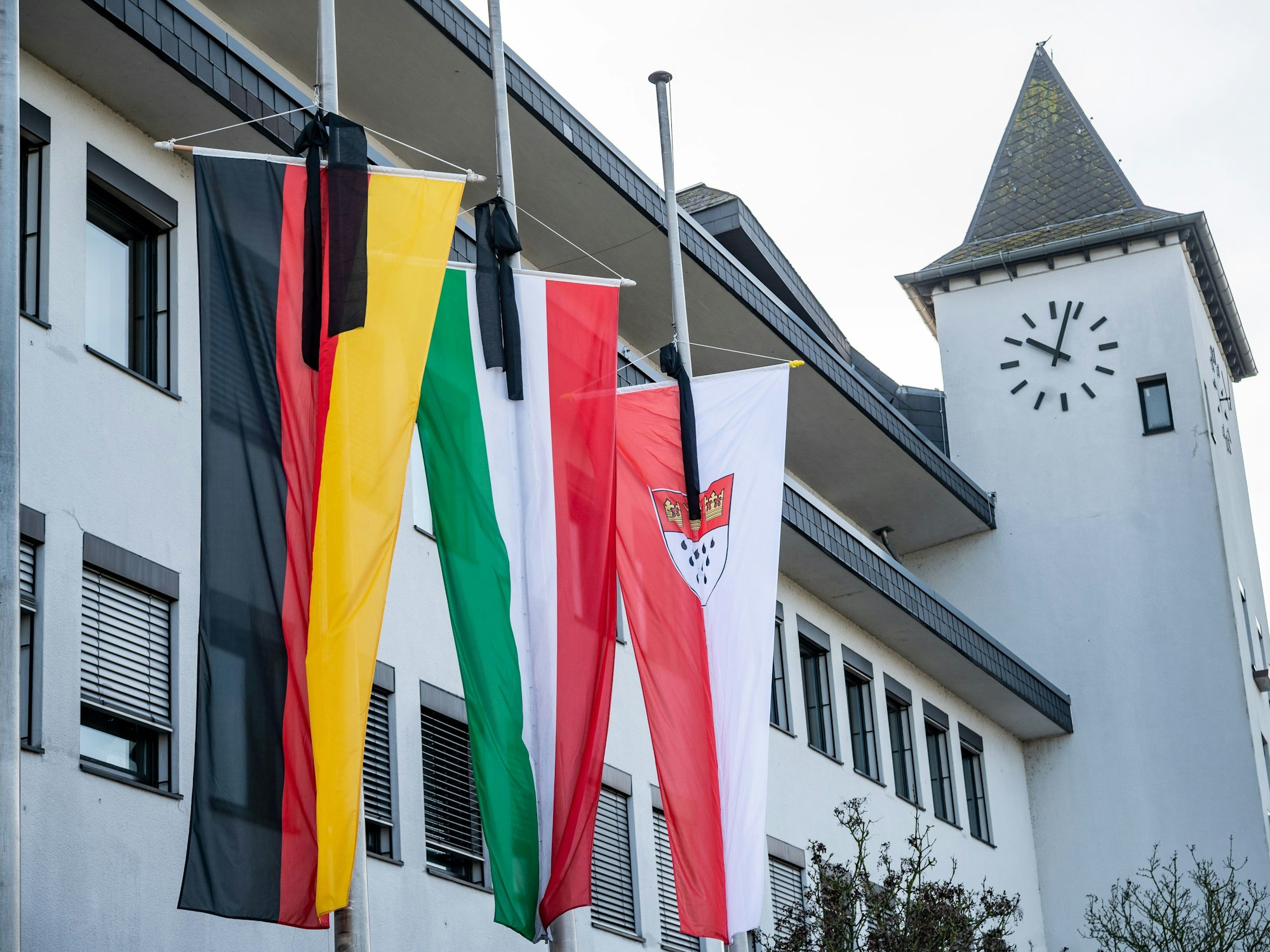 Am Bezirksrathaus Porz hängen drei Fahnen auf halbmast.