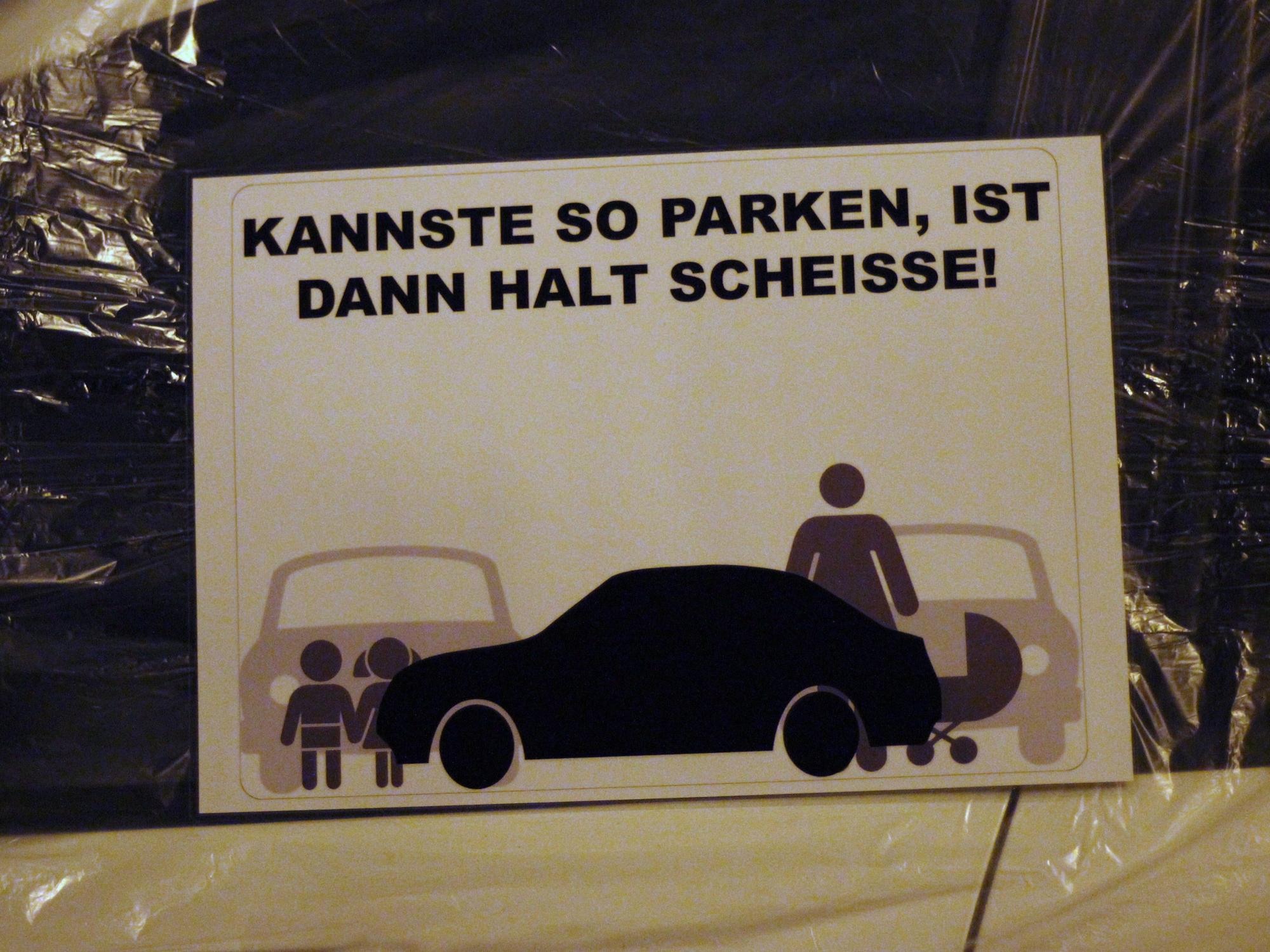 Das Symbolfoto zeigt einen Zettel an einer Autoscheibe mit den Worten "Kannste so parken, ist dann halt scheisse!".