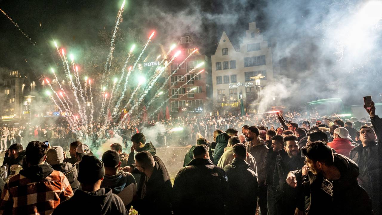 Menschen feiern draußen den Jahreswechsel und lassen Raketen steigen.