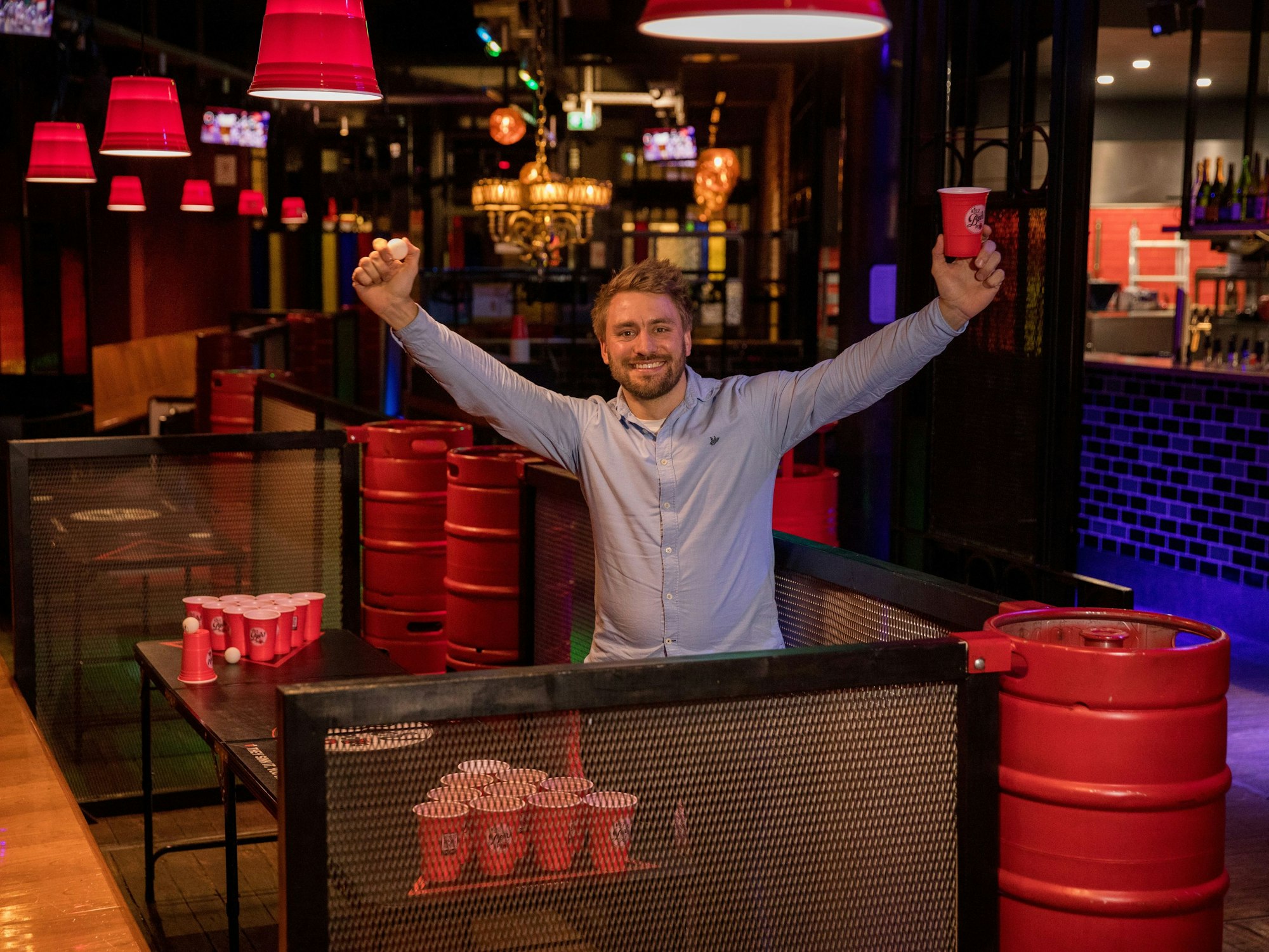 Beerpongbar-Besitzer Marcel Bethke jubelt mit beiden Armen in der Höhe.