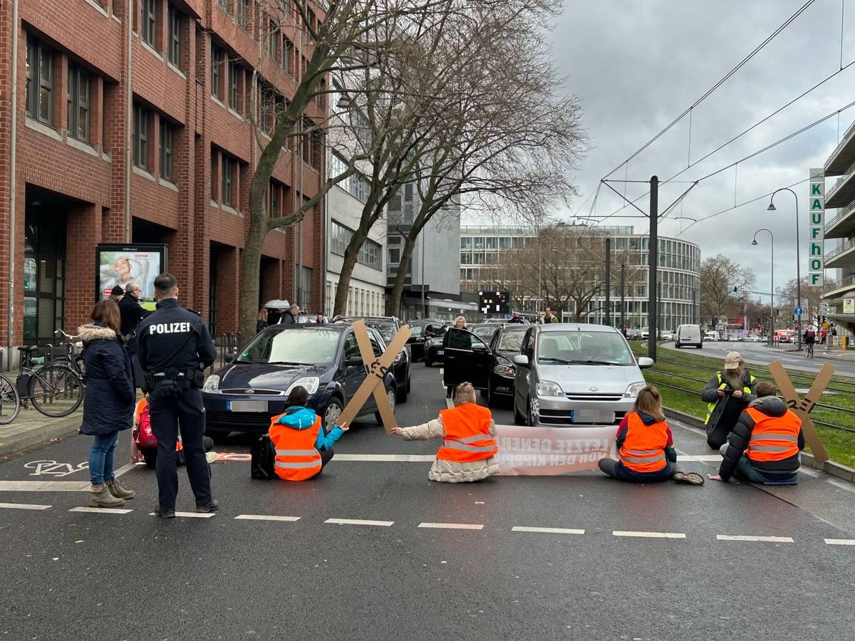 Aktivistinnen und Aktivisten der „Letzten Generation“ blockieren am Freitagmittag mit einer Sitzblockade eine der zentralen Verkehrsachsen in der Kölner Innenstadt.