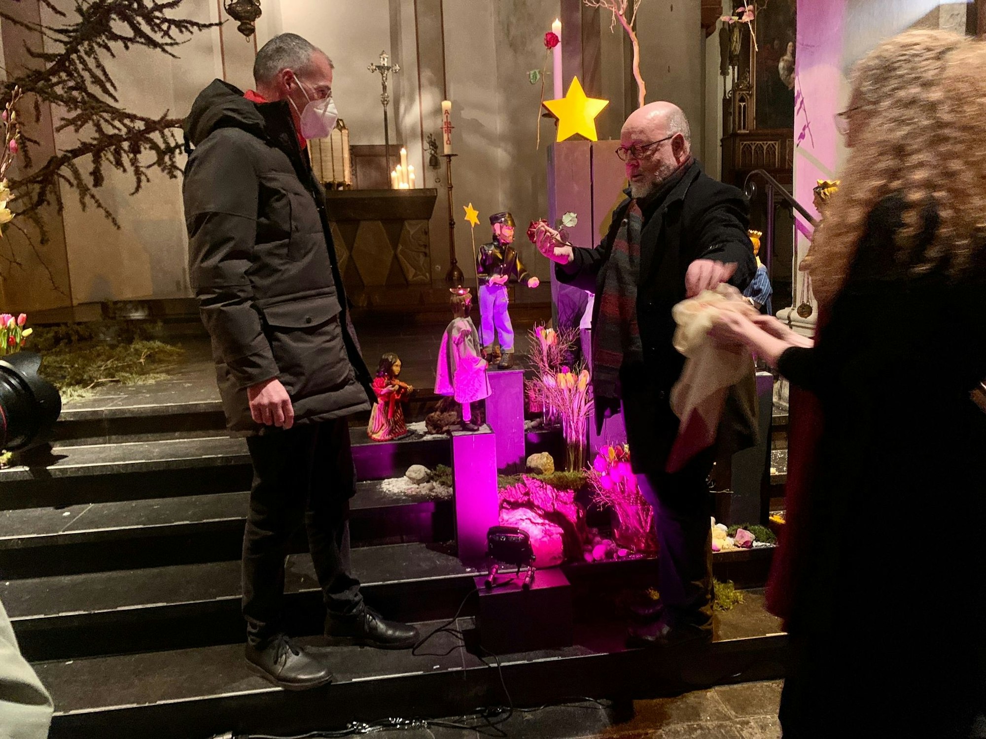 Pfarrer Bernd Mönkebüscher (l.) und der Kölner Pfarrer Benjamin Marx enthüllen eine neue Krippenfigur.