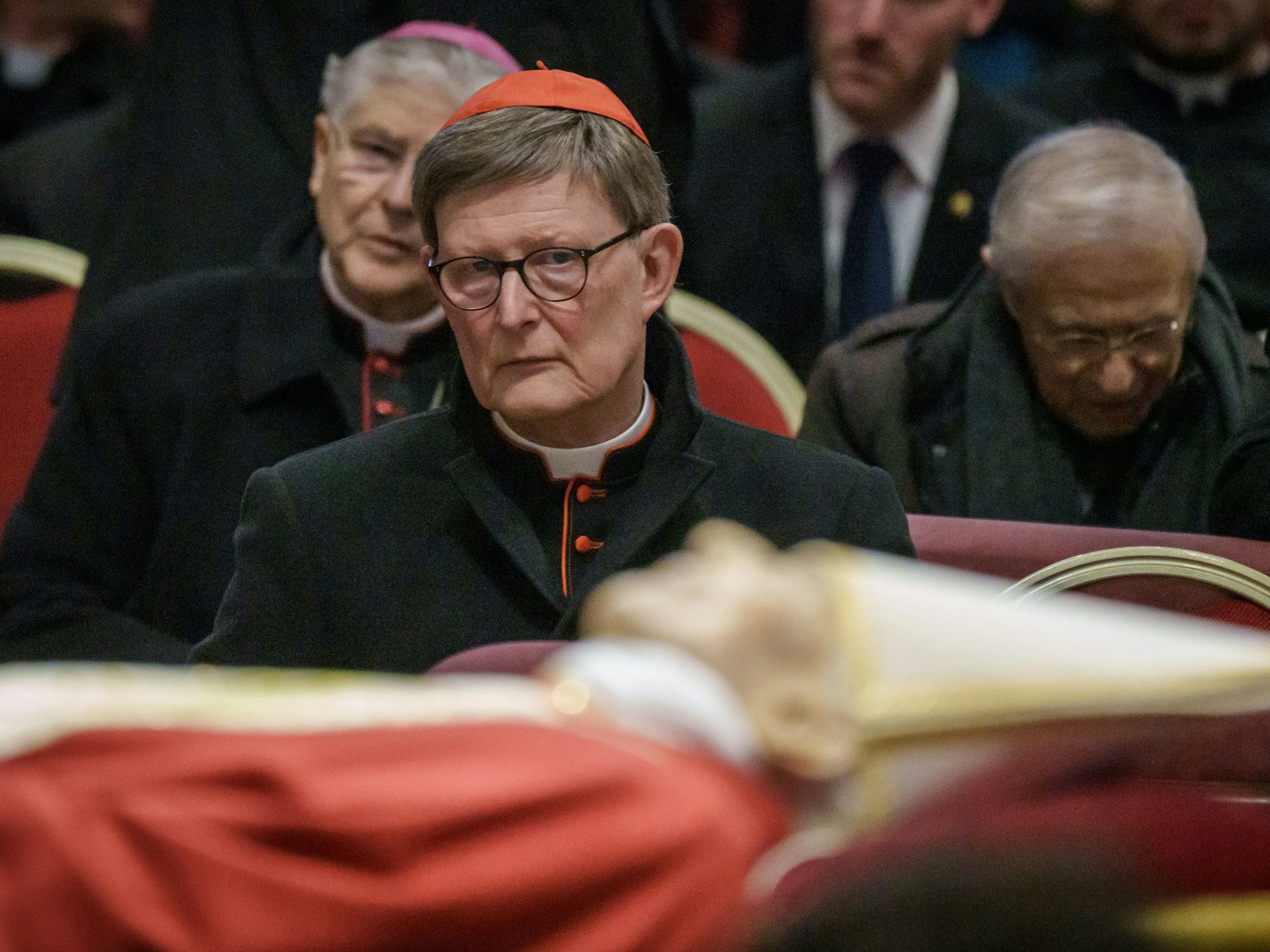 Kardinal Rainer Maria Woelki sitzt hinter dem Leichnam des verstorbenen Papstes Benedikt XVI., der im Petersdom aufgebahrt ist.