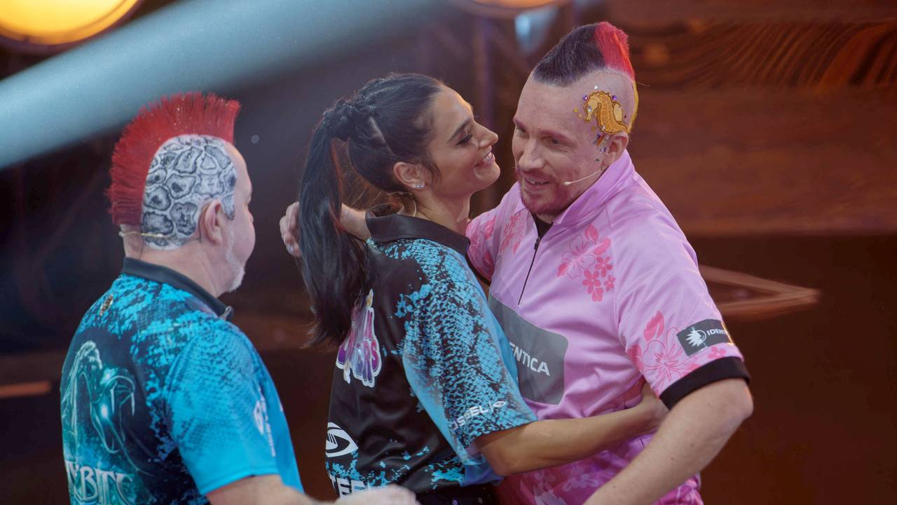 Der Profispieler Peter Wright und Amira und Oliver Pocher (l-r) stehen bei der ProSieben Promi-Darts-WM 2023 auf der Bühne.