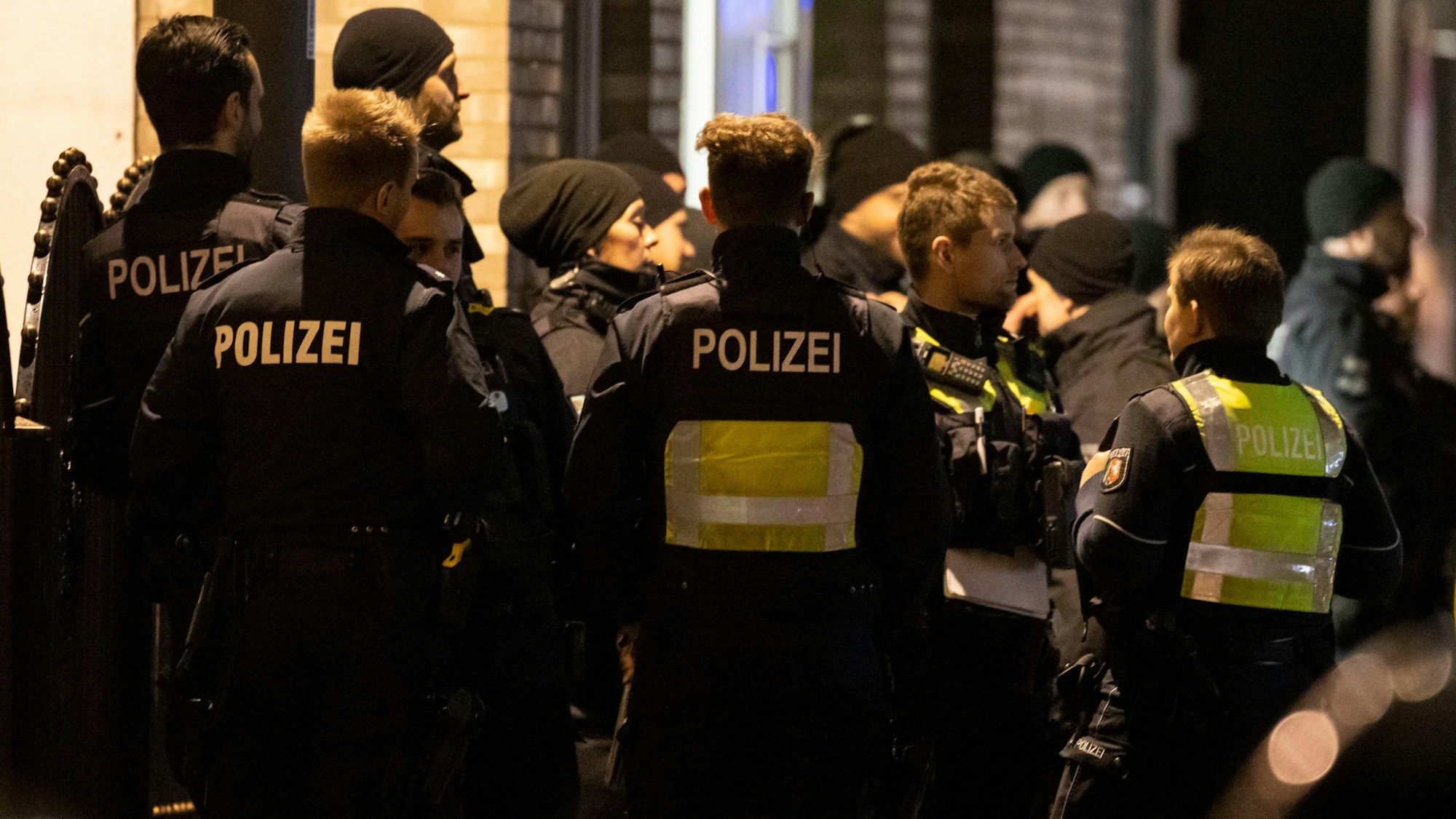 Einsatzkräfte der Polizei stehen vor einem Gebäude.