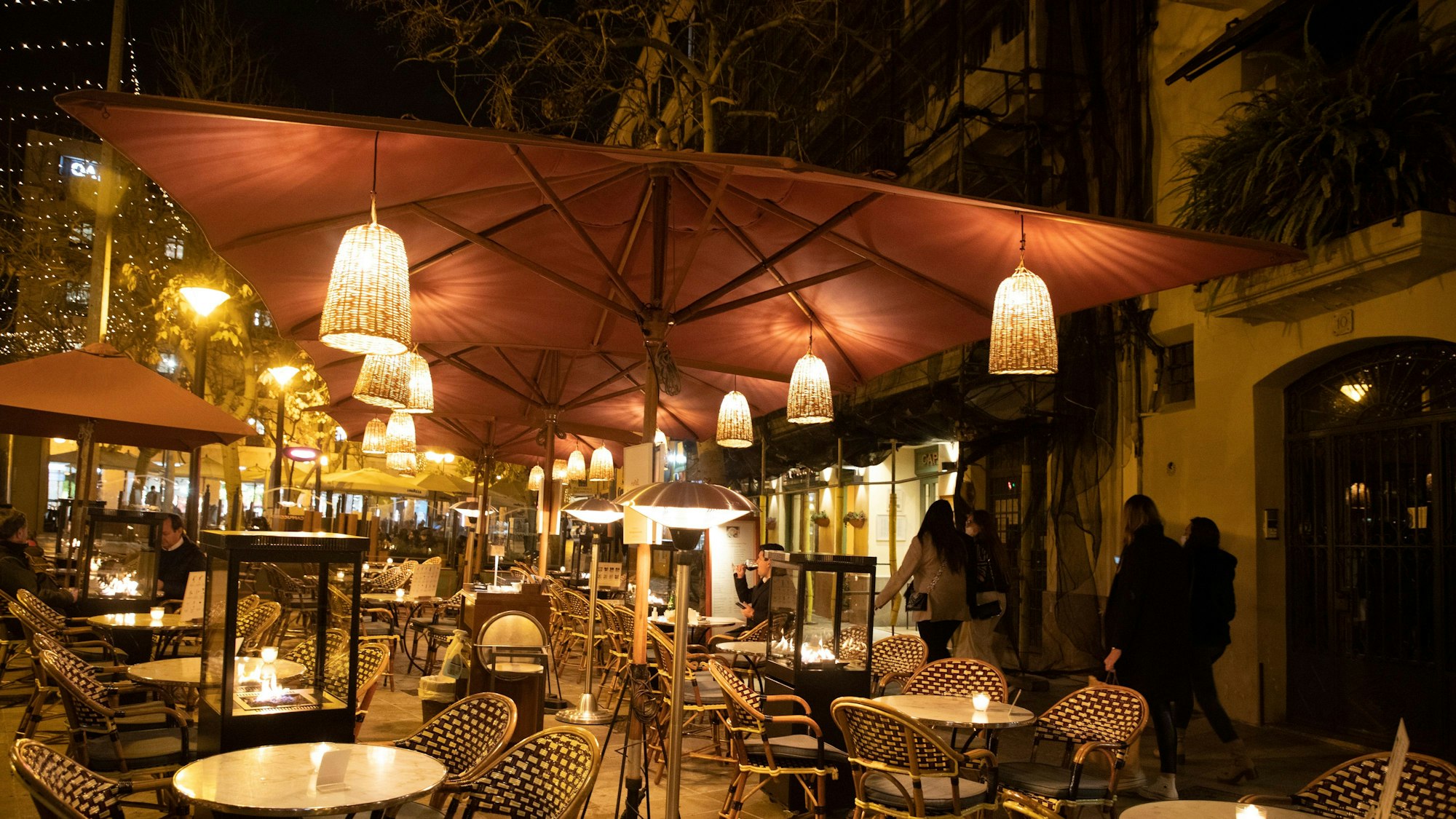 Das undatierte Symbolfoto zeigt den Außenbereich eines Restaurants mit Tischen, Stühlen und Laternen, die an Sonnenschirmen befestigt sind.