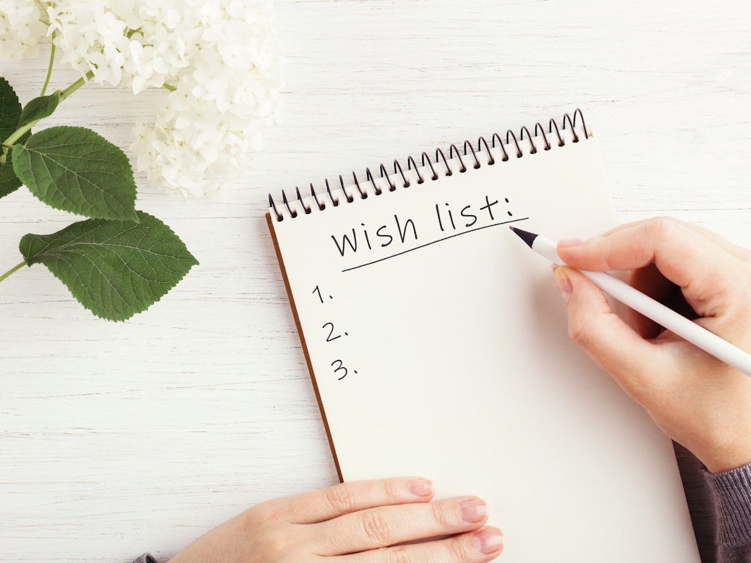 Wunschzettel im Notizbuch auf weißem Holztisch.