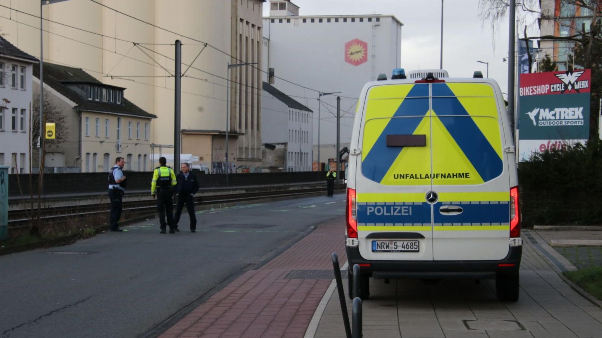 Der Bulli des Verkehrsunfallaufnahmeteams parkt an der Siegburger Straße, ein paar Meter entfernt stehen drei Einsatzkräfte.