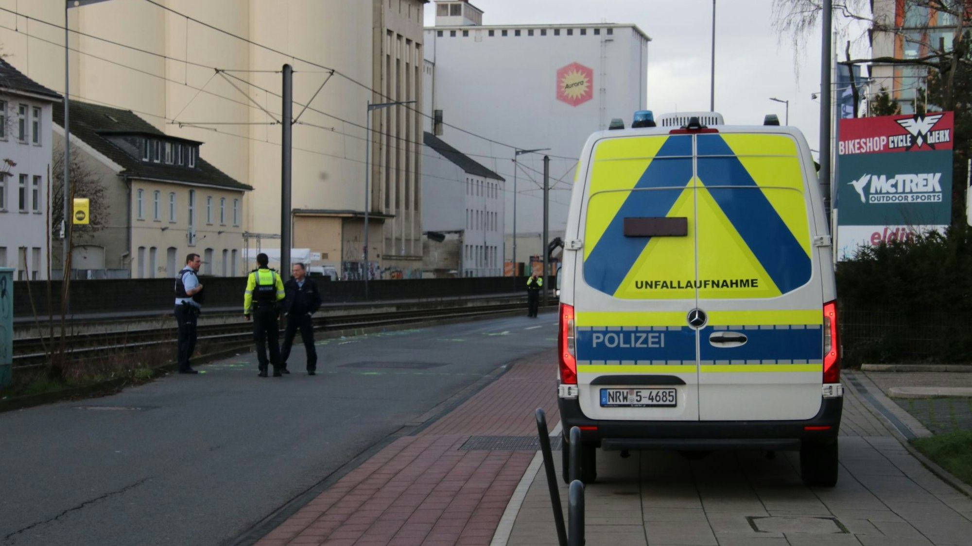 Der Bulli des Verkehrsunfallaufnahmeteams parkt an der Siegburger Straße, ein paar Meter entfernt stehen drei Einsatzkräfte.