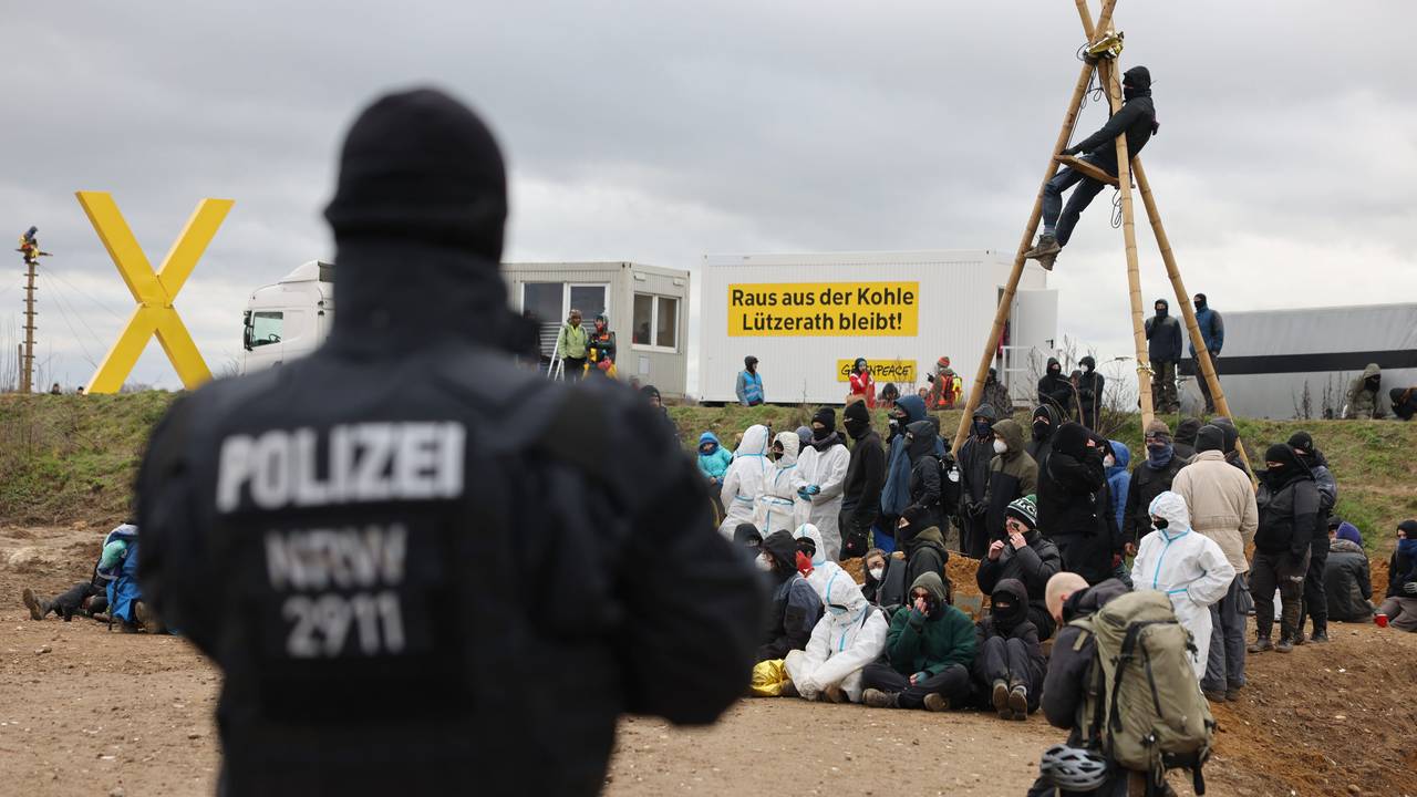 Ein Polizist beobachtet Klimaschutzaktivistinnen und -aktivisten, die am Rand des Tagebaus sitzen. Das Dorf Lützerath soll zur Erweiterung des Braunkohletagebaus Garzweiler II abgebaggert werden.
