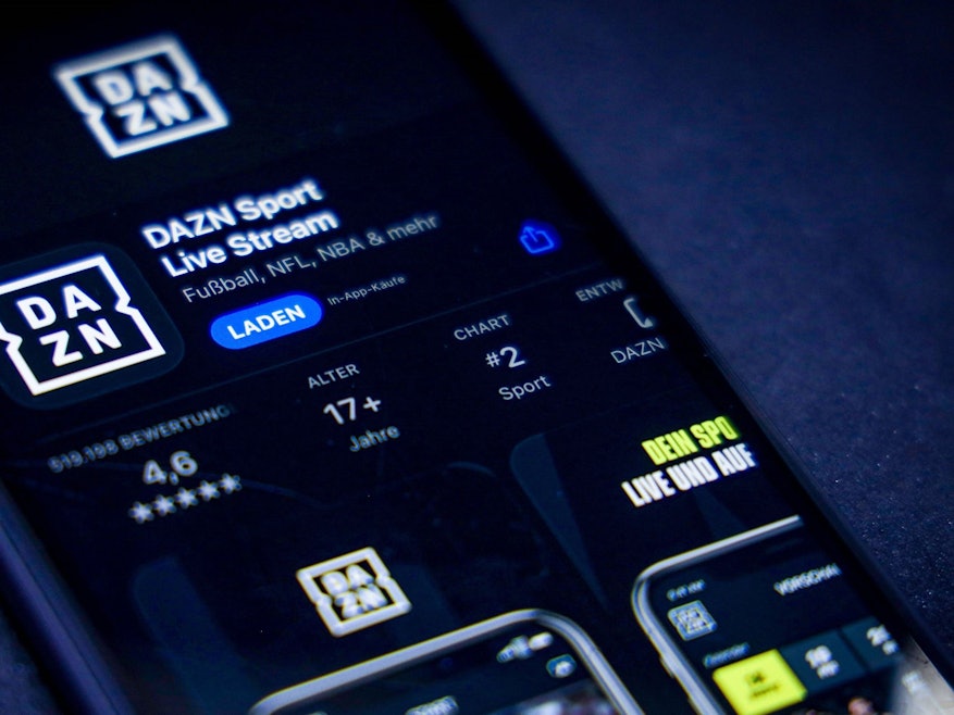 Ein Handy mit der DAZN-App ist auf einer Illustration zu sehen.