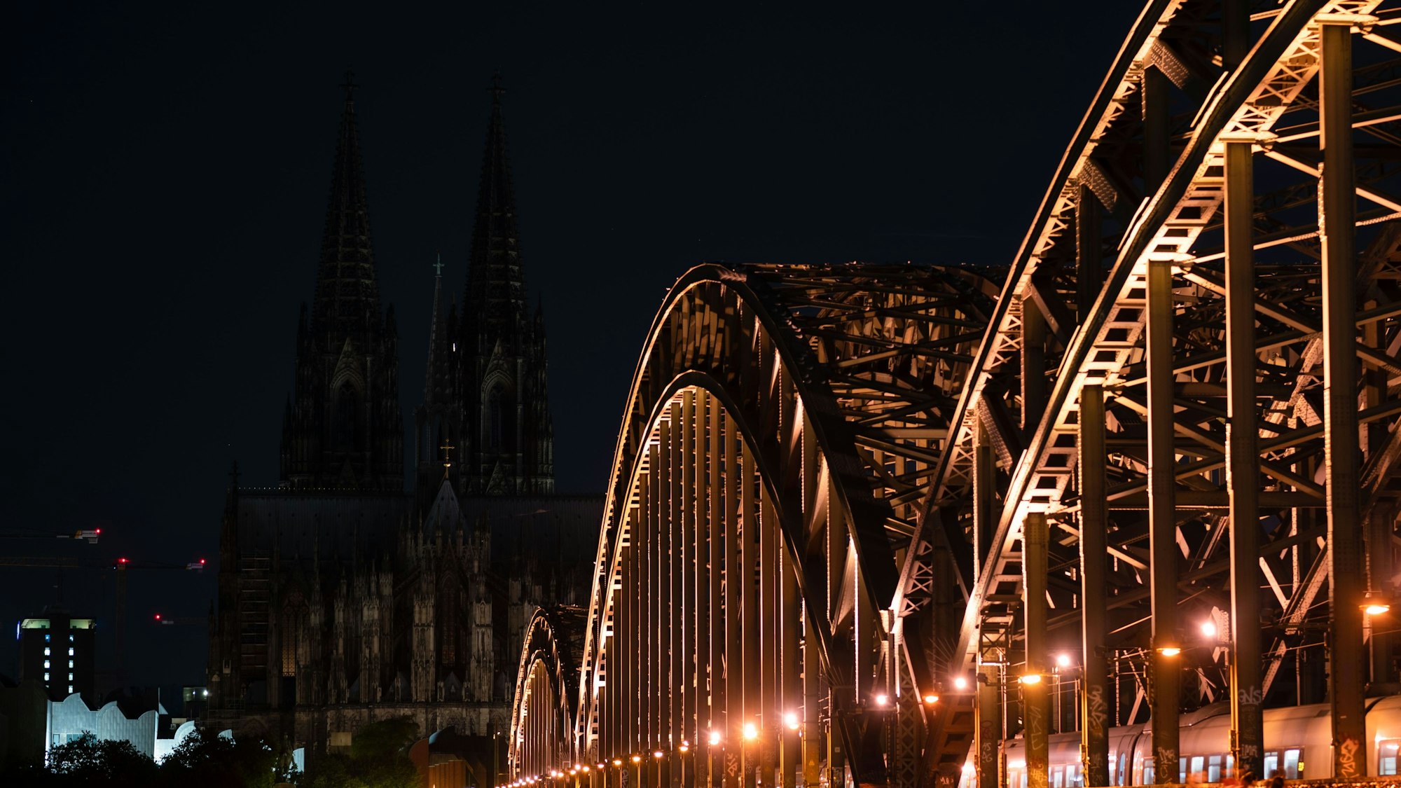 Unbeleuchtet ist der Kölner Dom nach 23 Uhr. Im Vordergrund die Hohenzollernbrücke.
