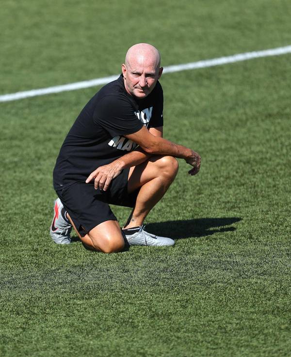 Frauenfußball-Trainer Paul Riley hockt auf dem Rasen.