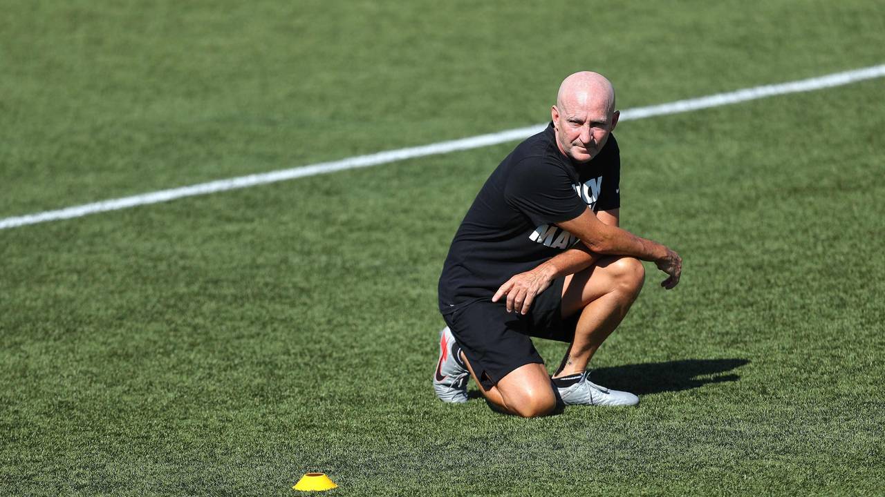 Frauenfußball-Trainer Paul Riley hockt auf dem Rasen.