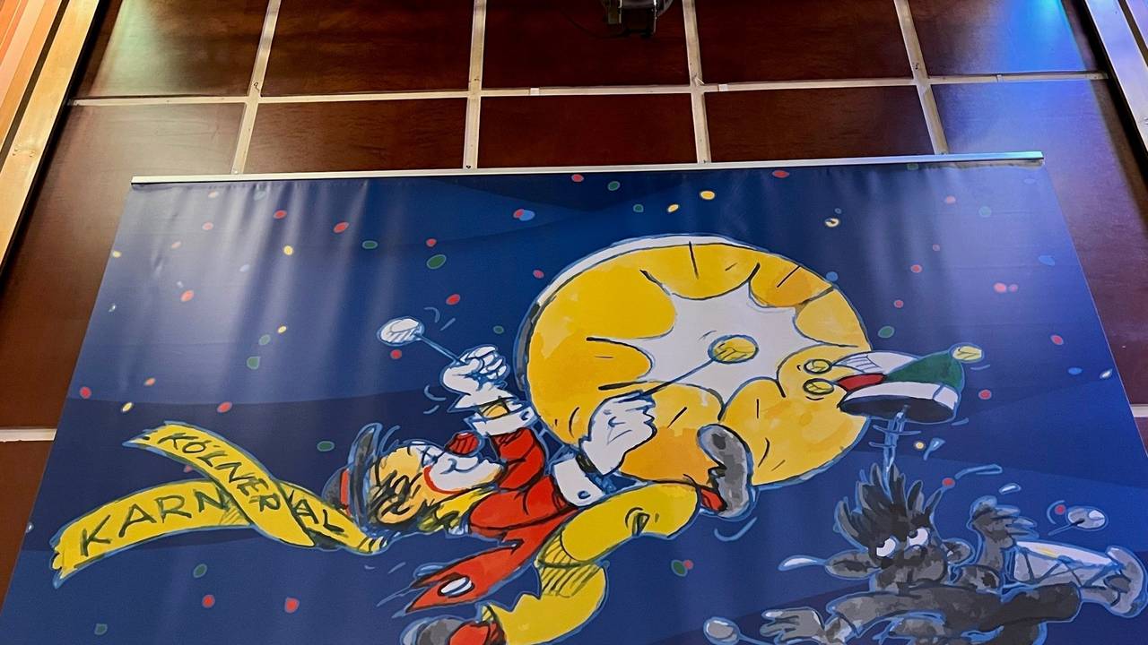 Zeichnung im Sartory-Saal: Ein Clown tritt einem Mann in den Hintern.