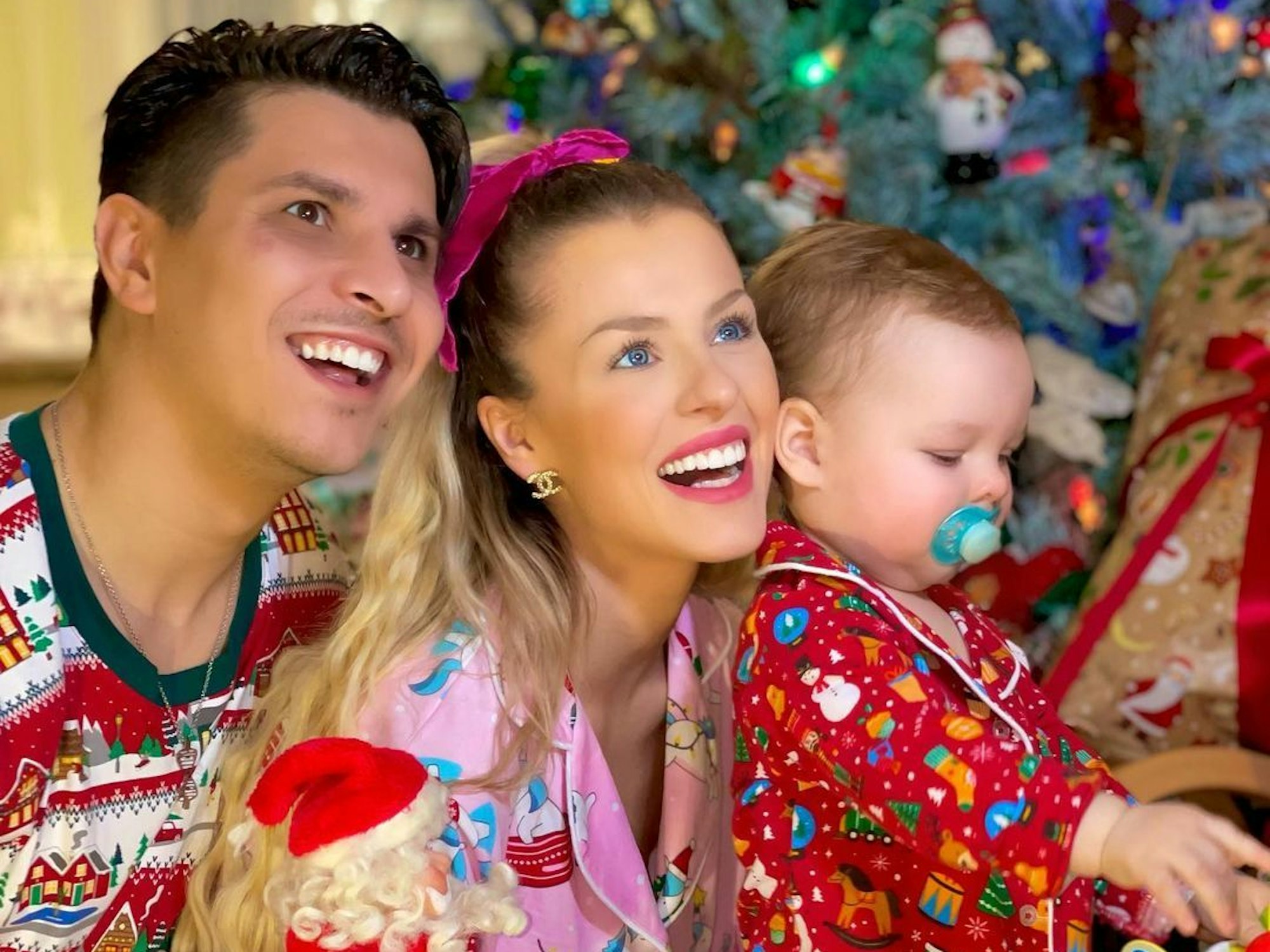 Patricija Ionel und Alexandru Ionel freuen sich mit ihrem Sohn vor dem Weihnachtsbaum.