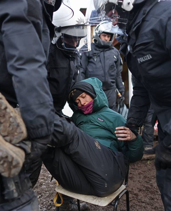Polizisten tragen bei der Räumung von Lützerath eine Demonstrantin fort.
