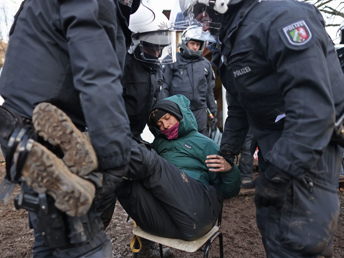 Polizisten tragen bei der Räumung von Lützerath eine Demonstrantin fort.