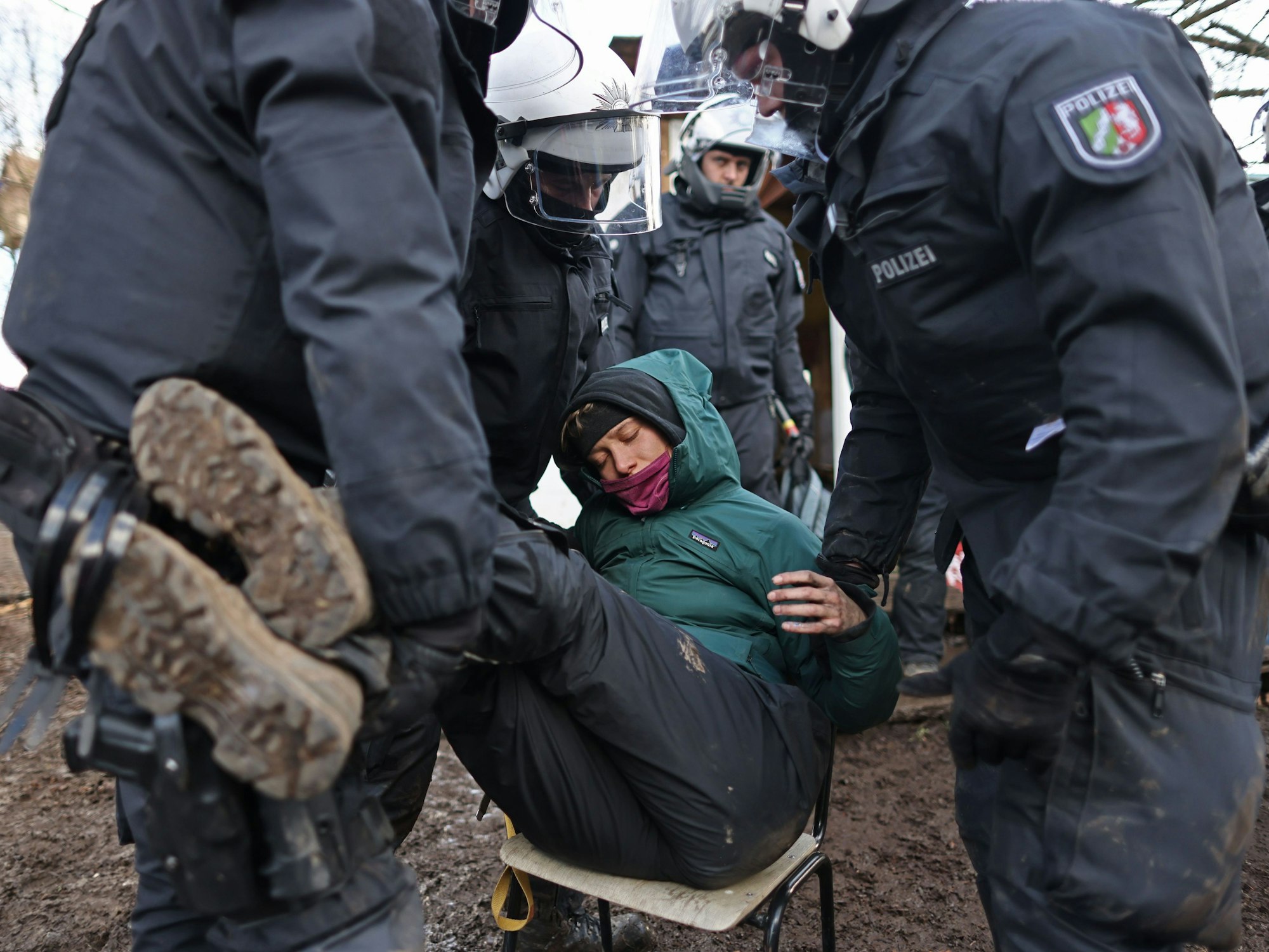 Polizisten tragen bei der Räumung von Lützerath eine Demonstrantin fort.