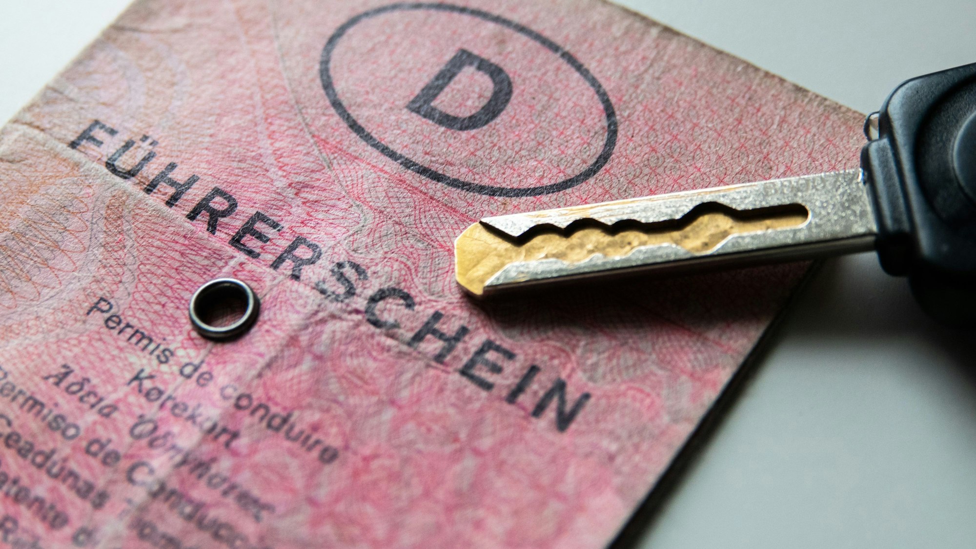 Ein alter rosafarbener Führerschein liegt auf einem Tisch. Daneben liegt ein Autoschlüssel.