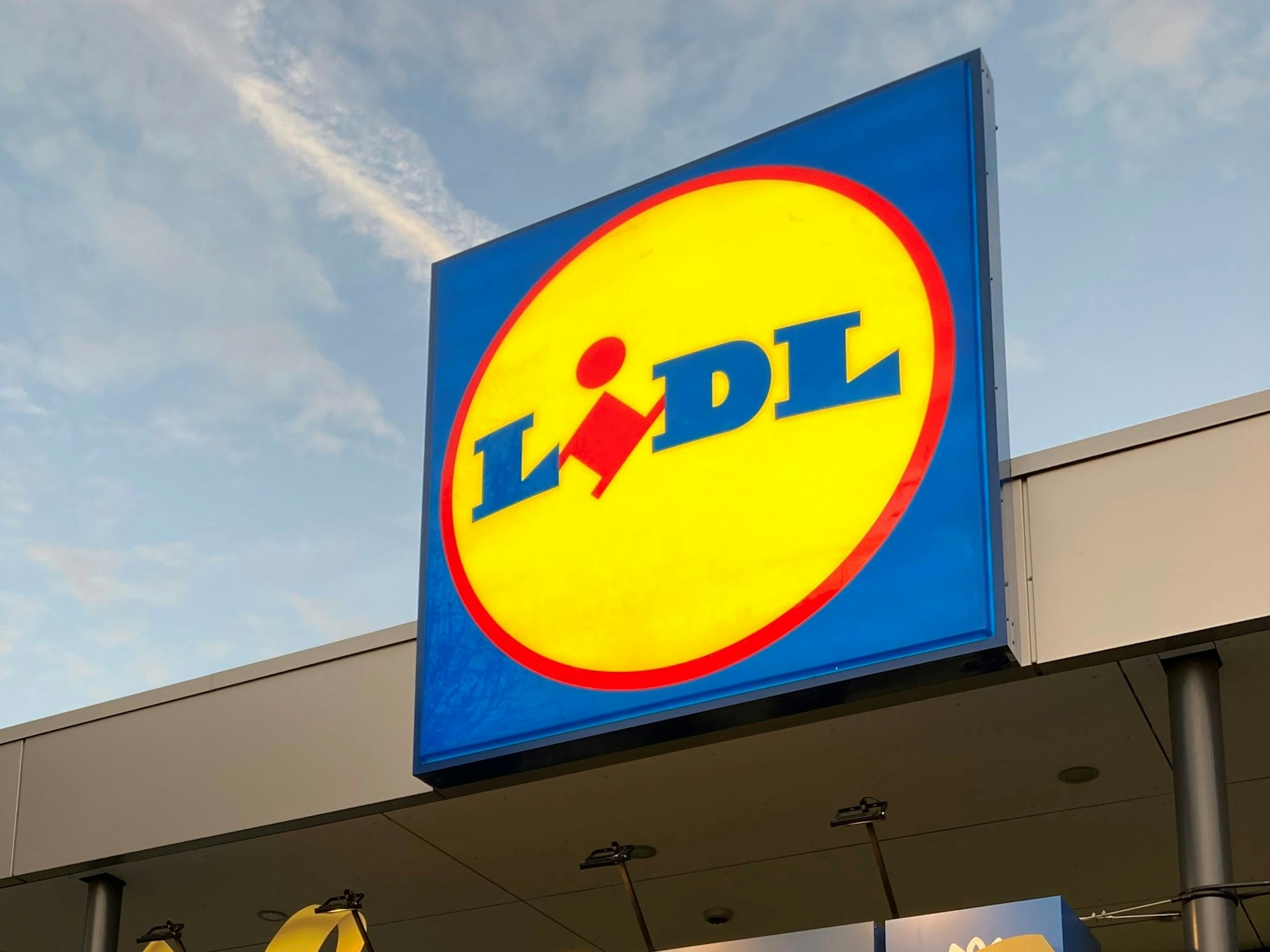 Hier zu sehen: Das bunte Logo des Discounters Lidl leuchtet über einer Supermarkt-Filiale.