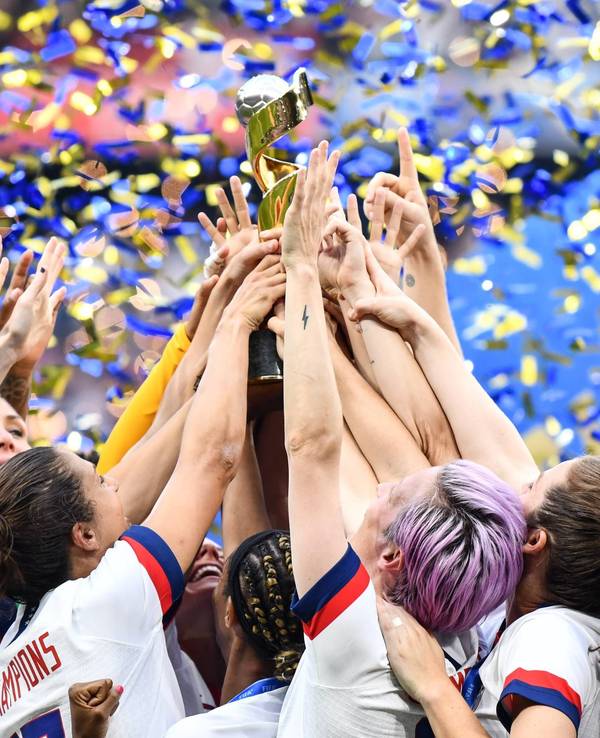 Viele Hände greifen zum Pokal, der mittig hochgehalten wird.