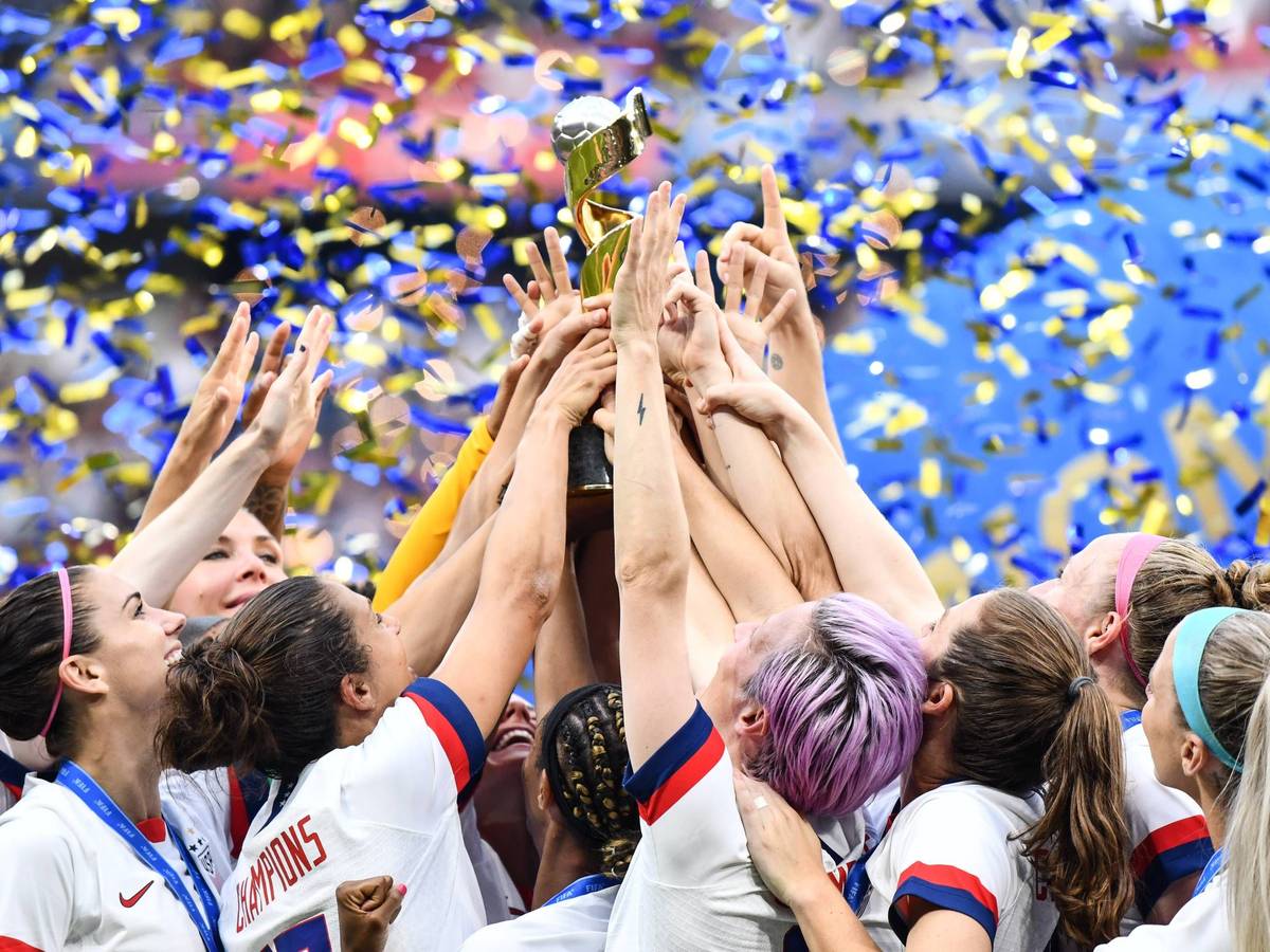 Viele Hände greifen zum Pokal, der mittig hochgehalten wird.