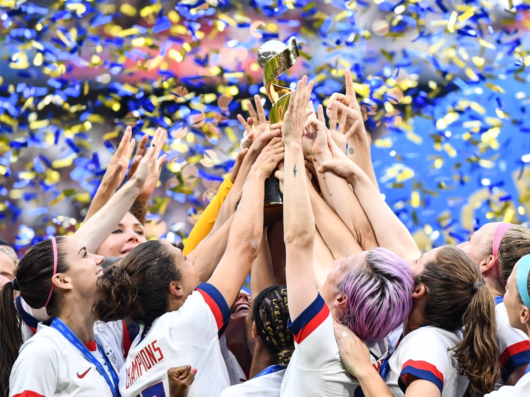 Viele Hände greifen zum Pokal, der mittig hochgehalten wird.