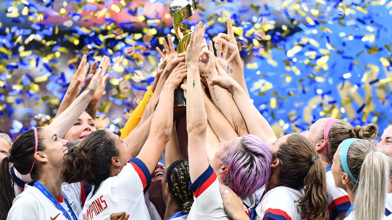 Viele Hände greifen zum Pokal, der mittig hochgehalten wird.