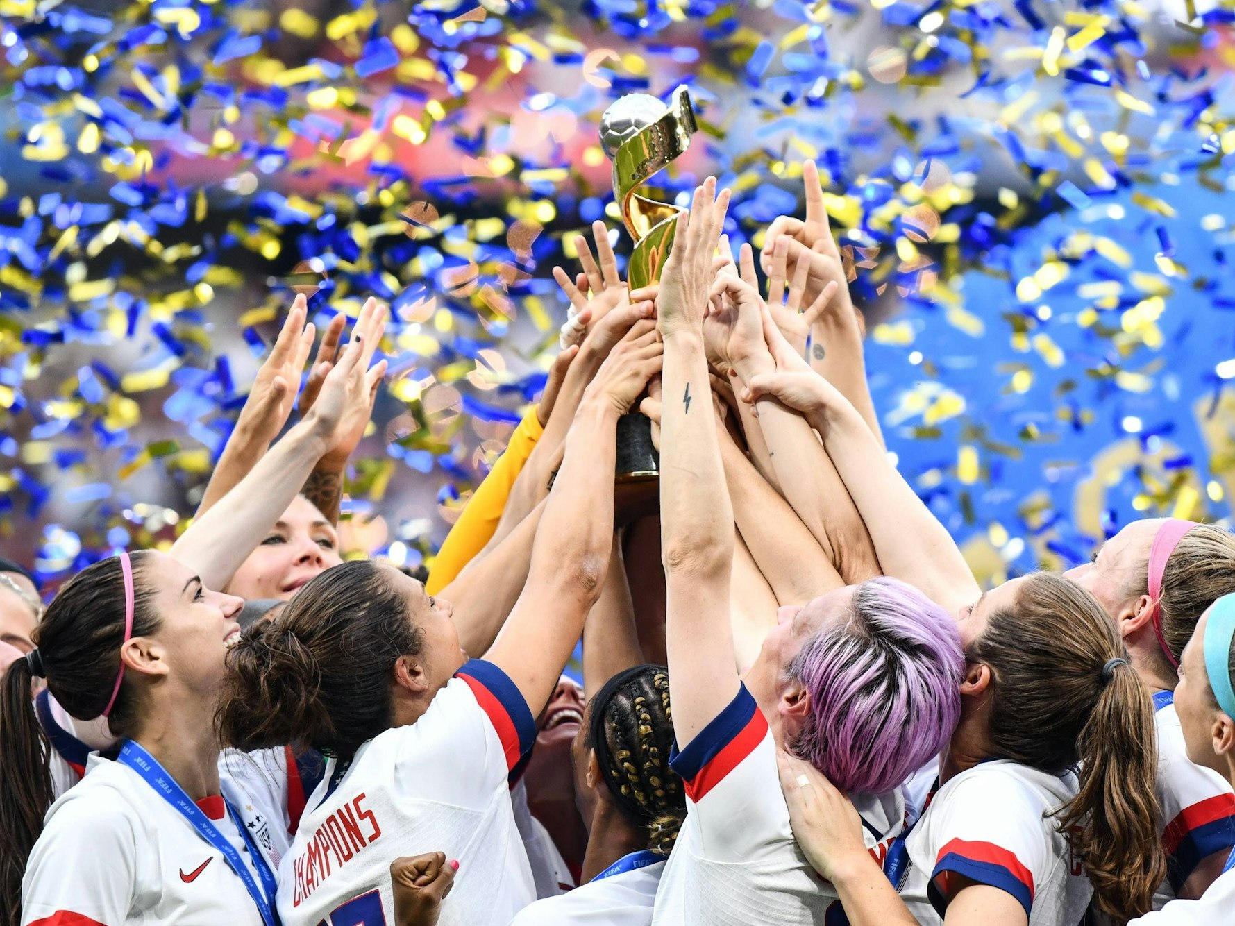 Viele Hände greifen zum Pokal, der mittig hochgehalten wird.