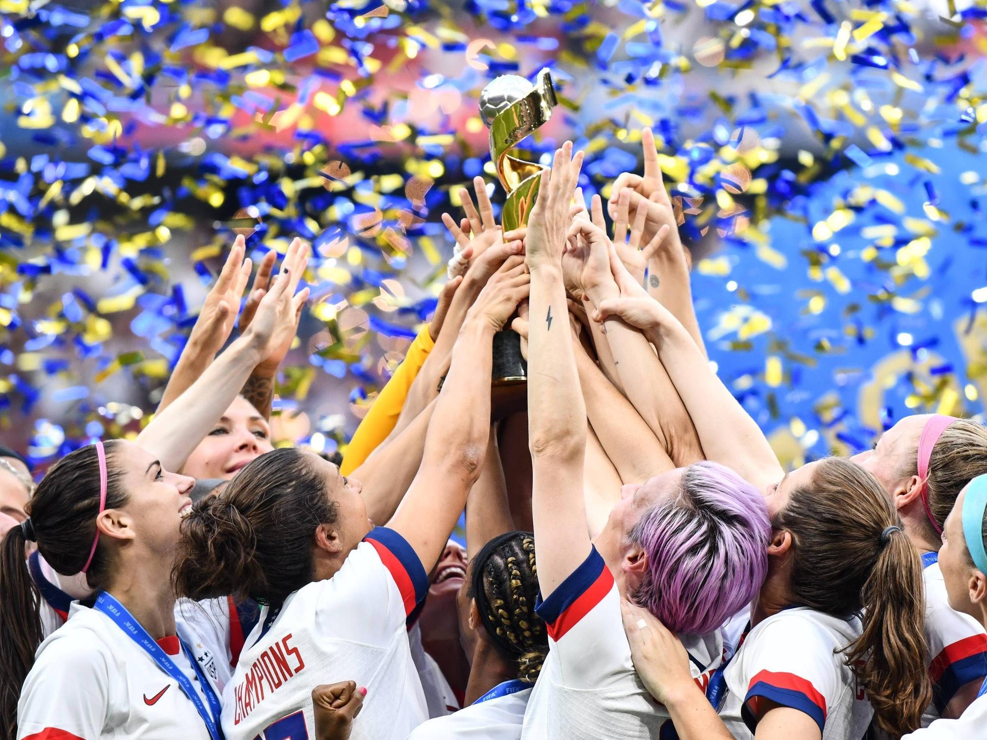 Viele Hände greifen zum Pokal, der mittig hochgehalten wird.