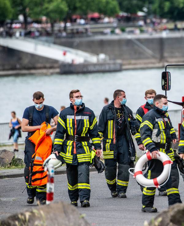 Feuerwehrmänner stehen am Rhein.