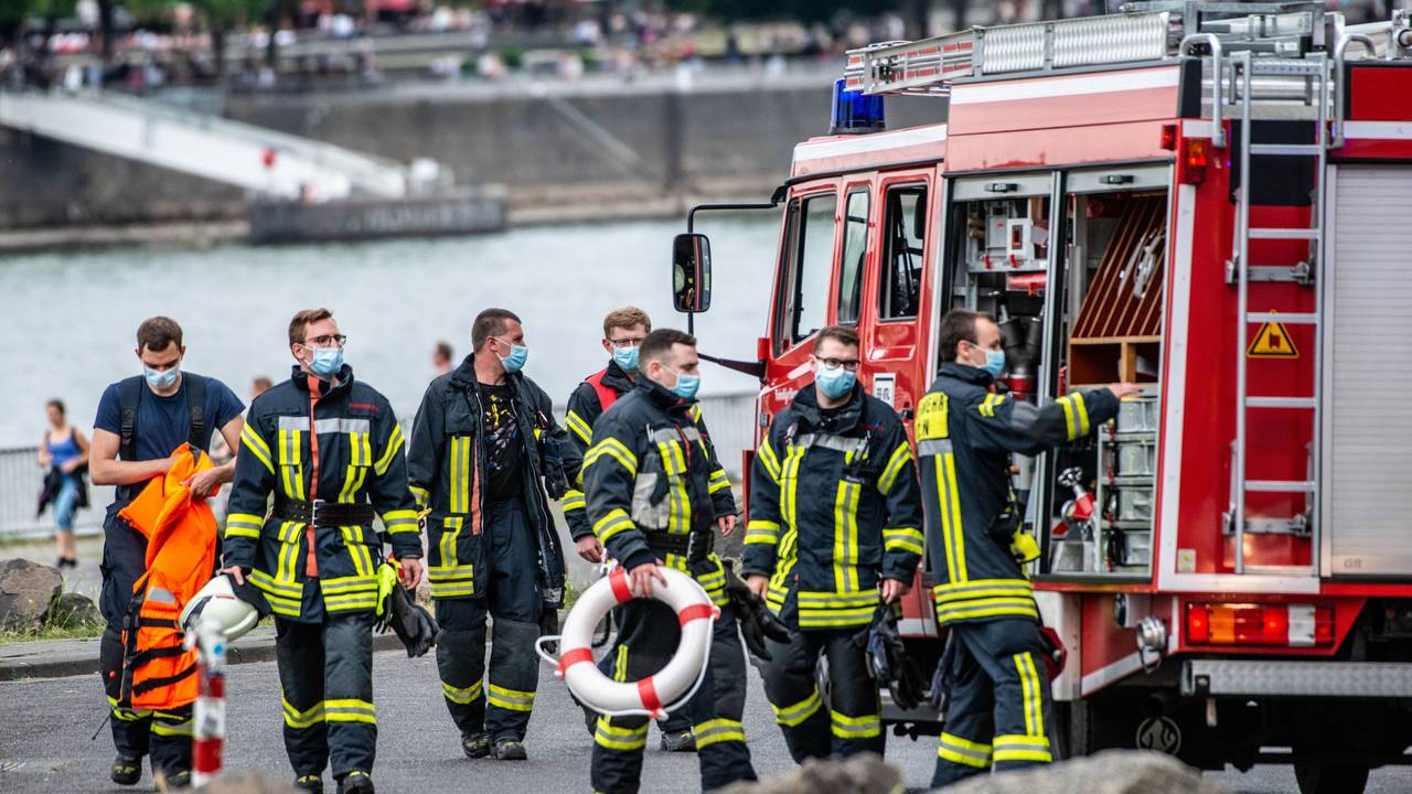 Feuerwehrmänner stehen am Rhein.